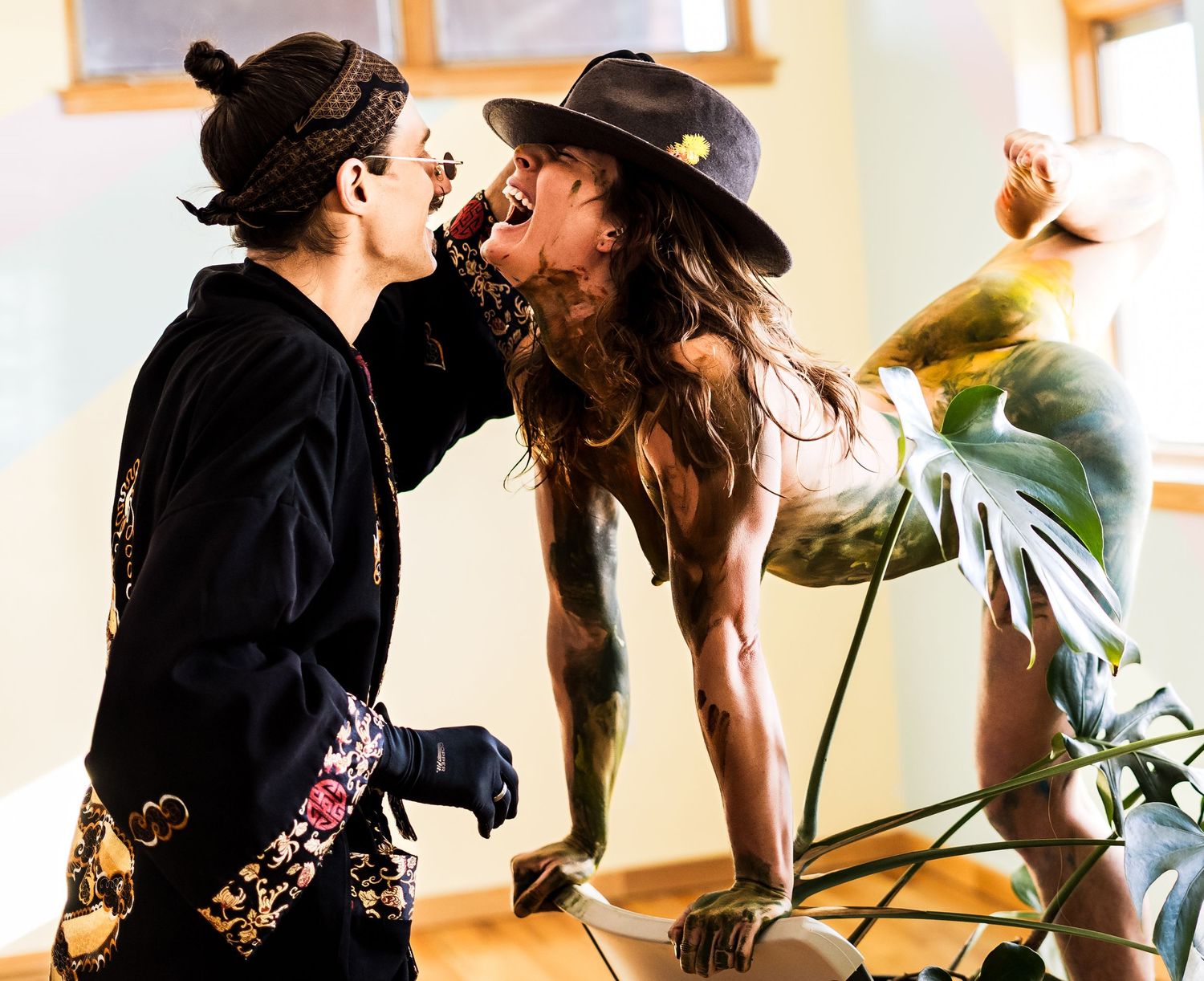 Romantic couple in bohemian style clothing share an intimate moment in a sunlit room.