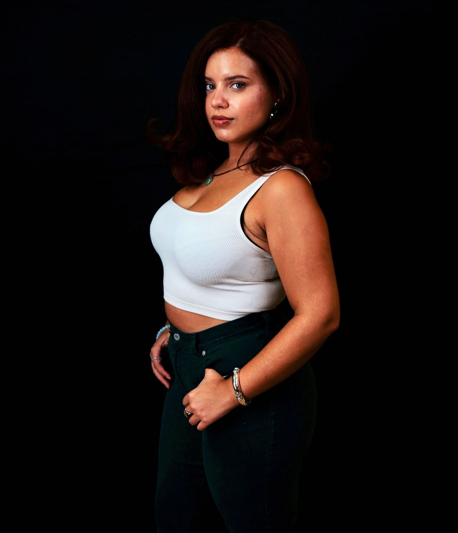 Dramatic lighting highlights white top and dark pants in studio setting.