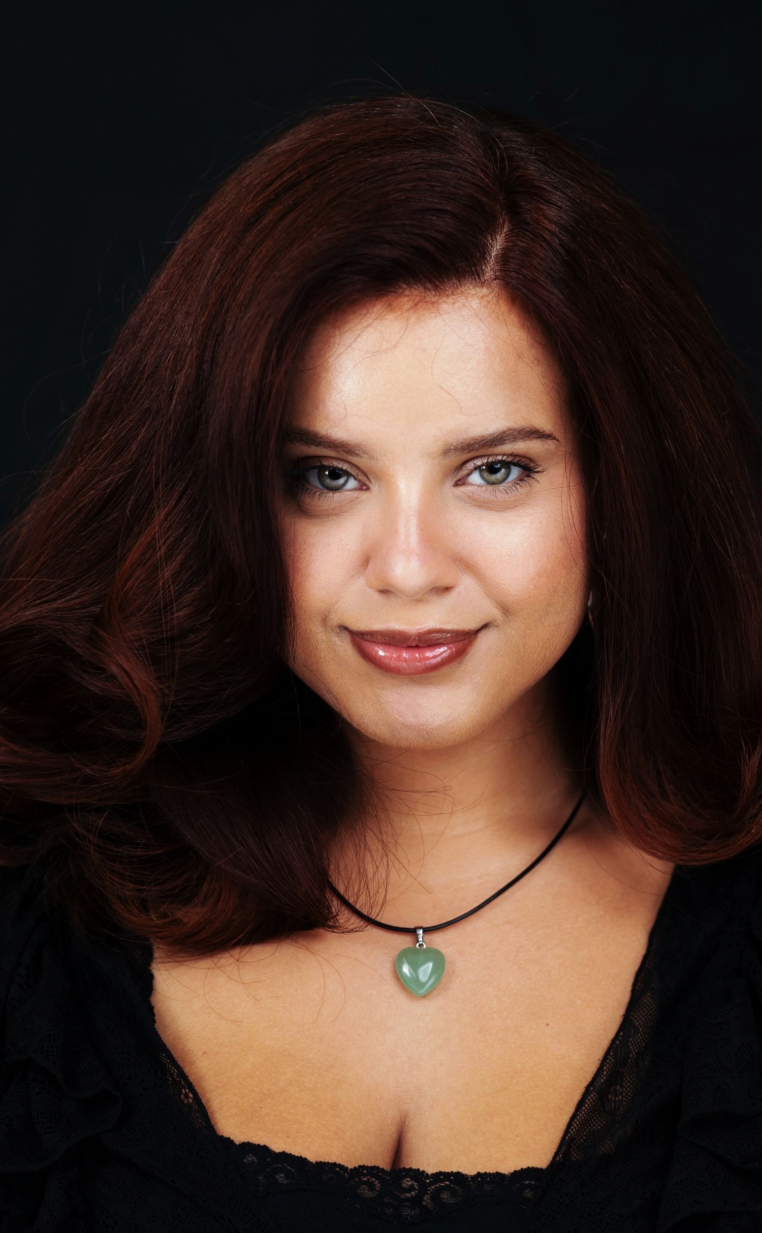 Portrait with dark background featuring jade pendant necklace.