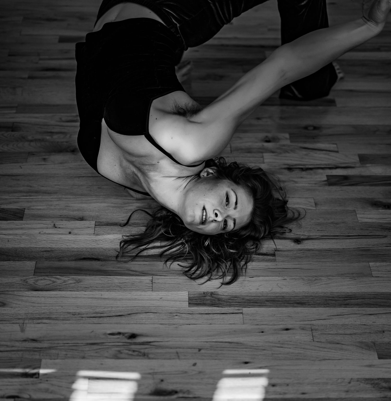 Black and white floor poses series showing dramatic angles on wooden surface.