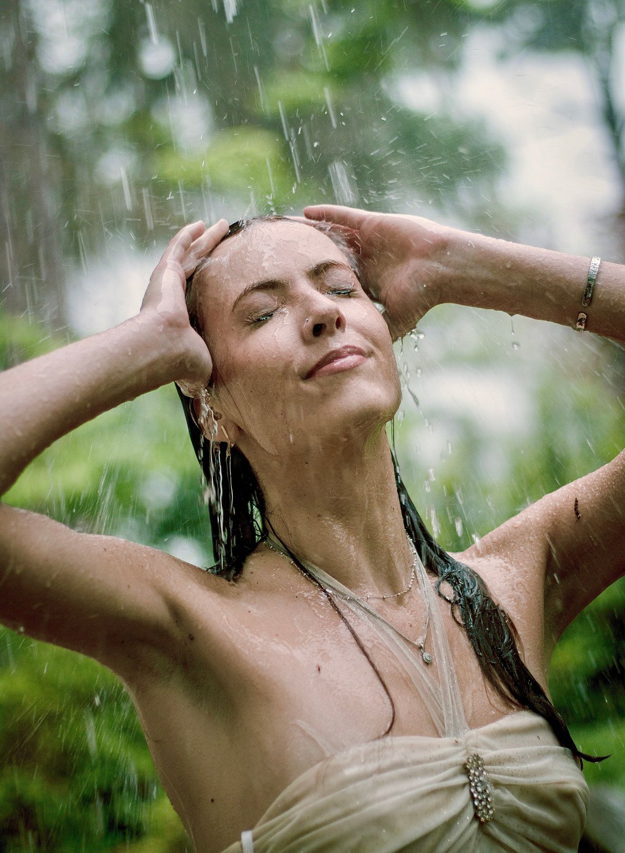 Summer rain shower in garden with water droplets and green foliage.