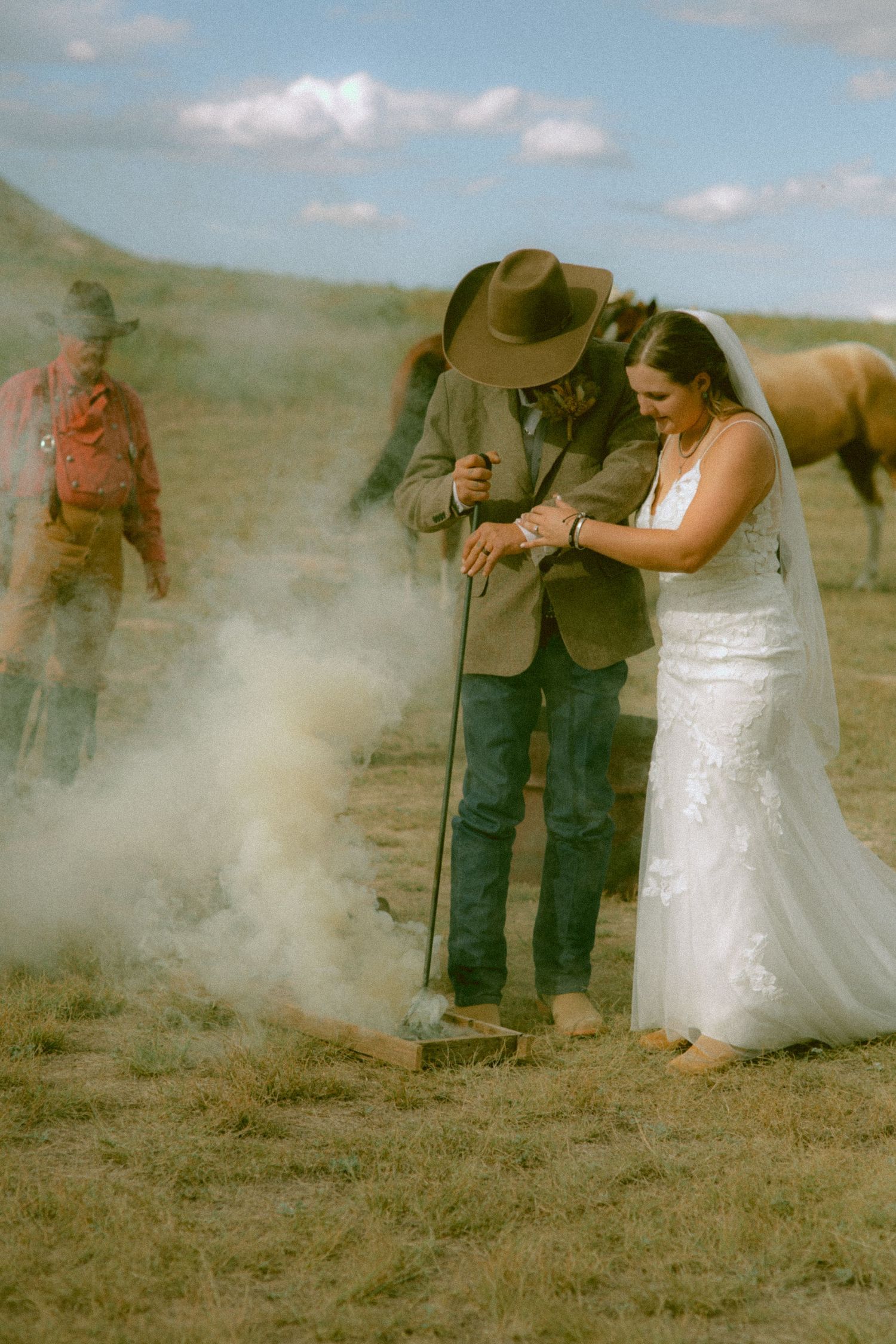 A western bride and groom in wedding attire using a brand during their ceremony in Nebraska.
