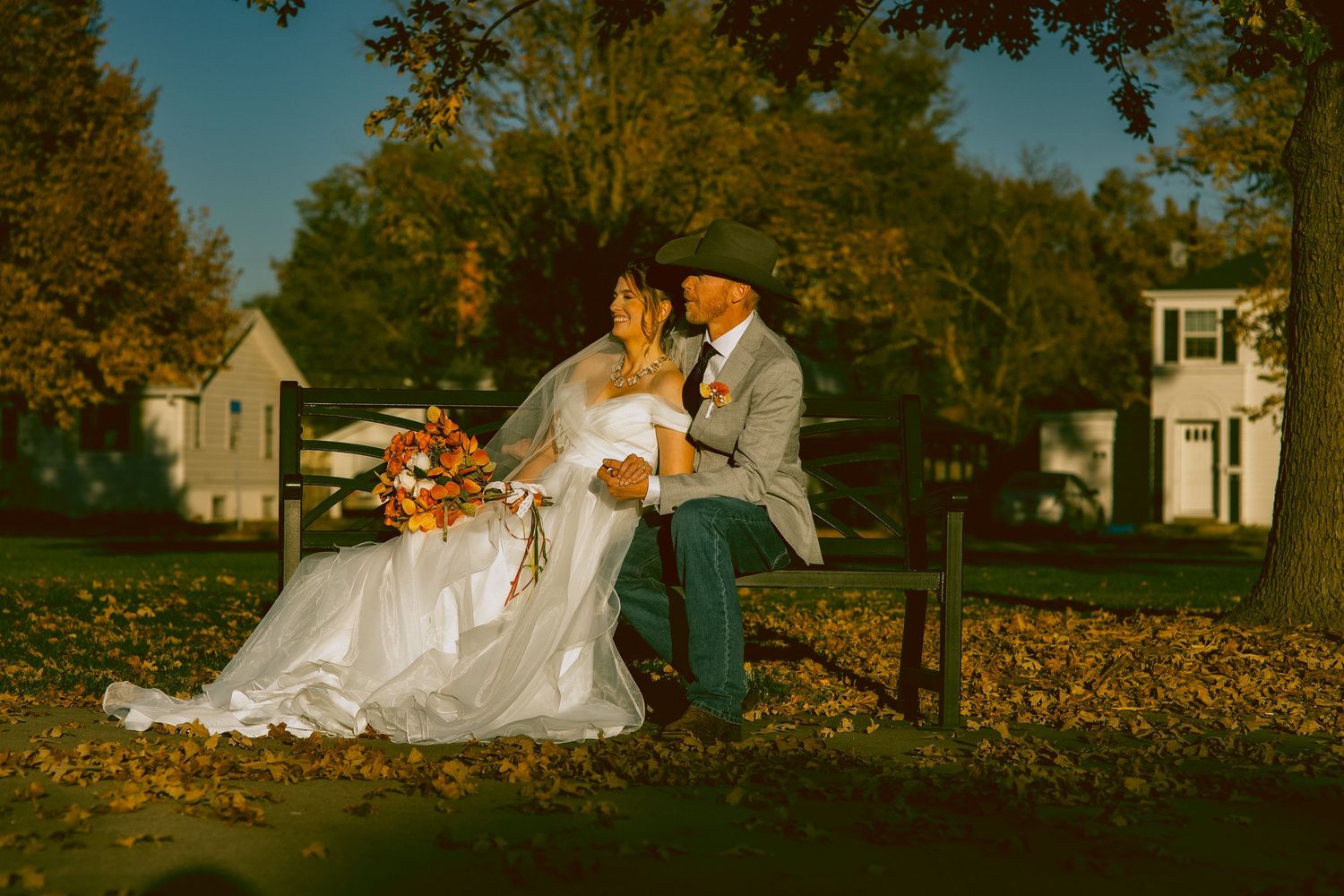 Romantic autumn wedding photo with couple on bench surrounded by fallen leaves in Scottsbluff Nebraska.