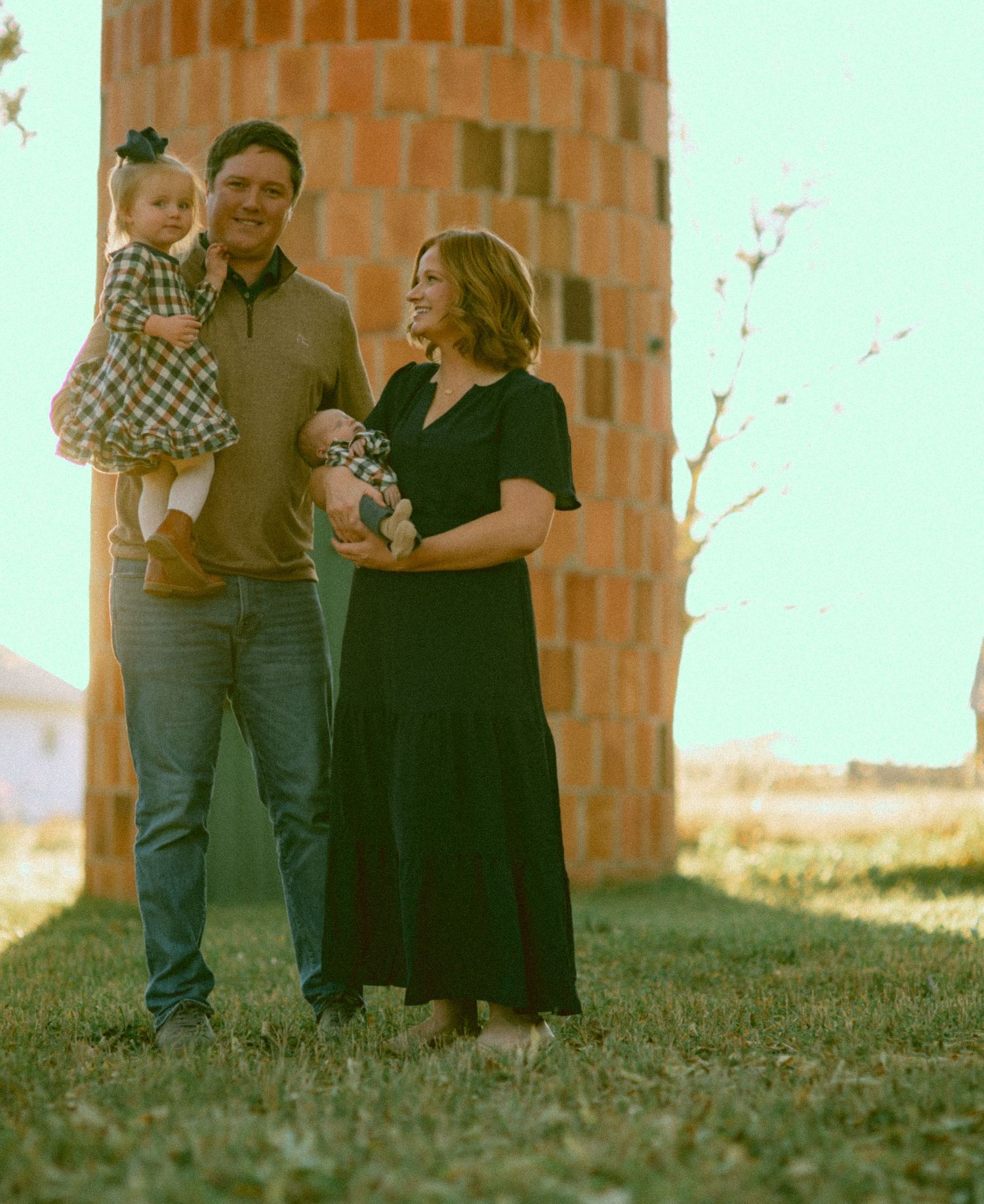 Family gathering outdoors near a brick wall during a photo session in Kimball Nebraska.