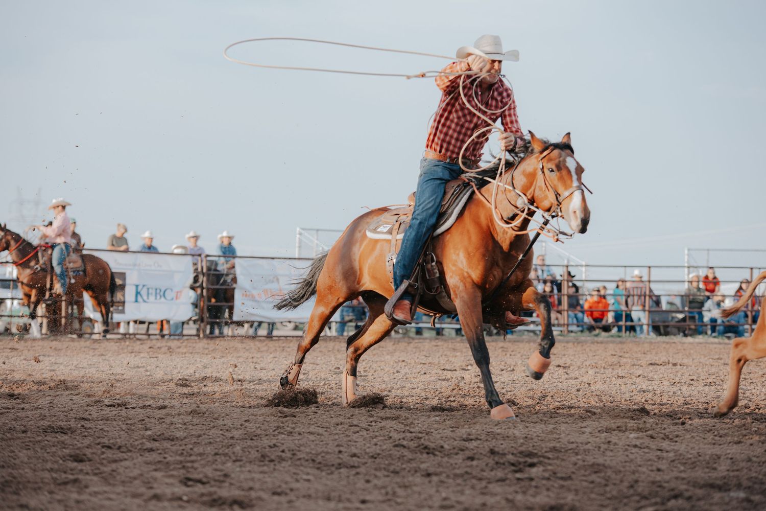 Cowboys competing in rodeo events on horseback in a dirt arena during daytime in Cheyenne Wyoming.
