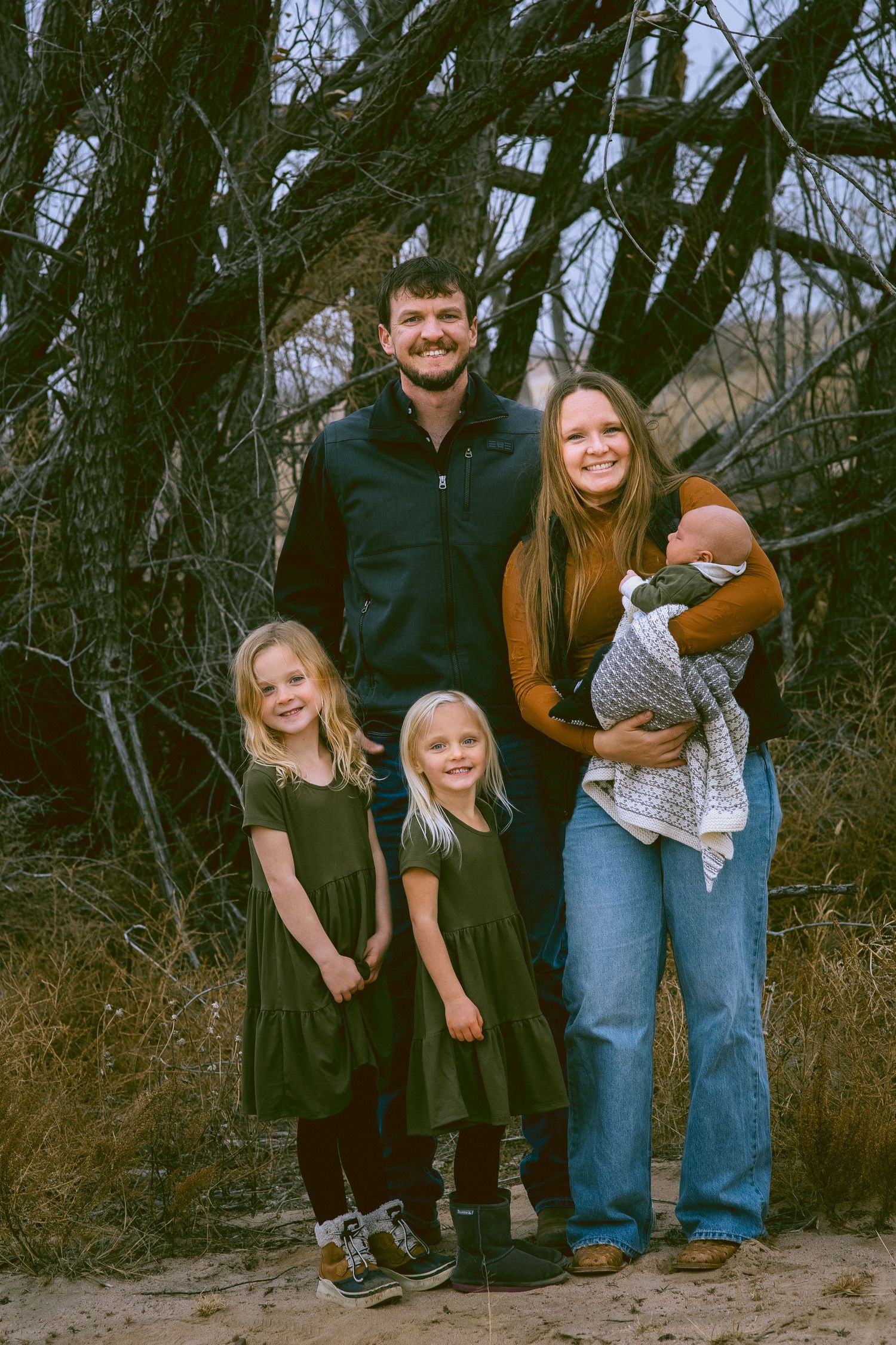 Family portrait in front of bare winter trees at dusk in Kimball Nebraska