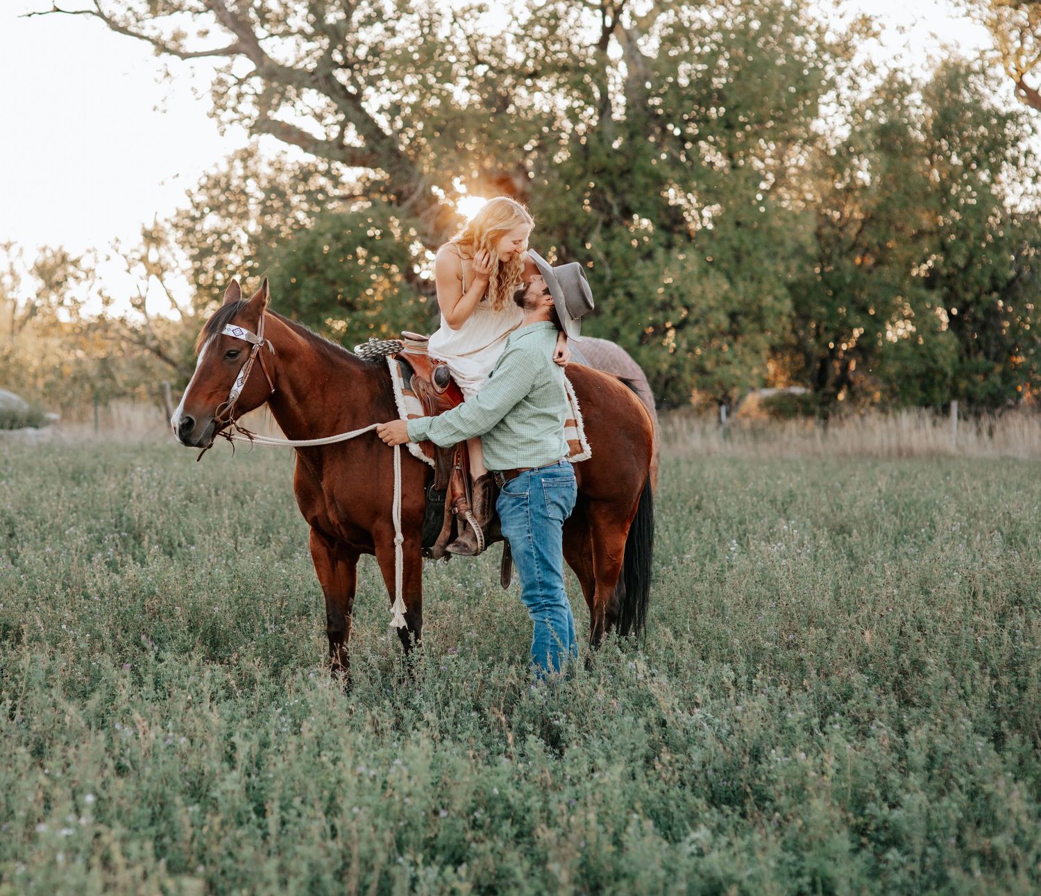 A western engaged couple looking at each other with their horse in a hay field in Nebraska.
