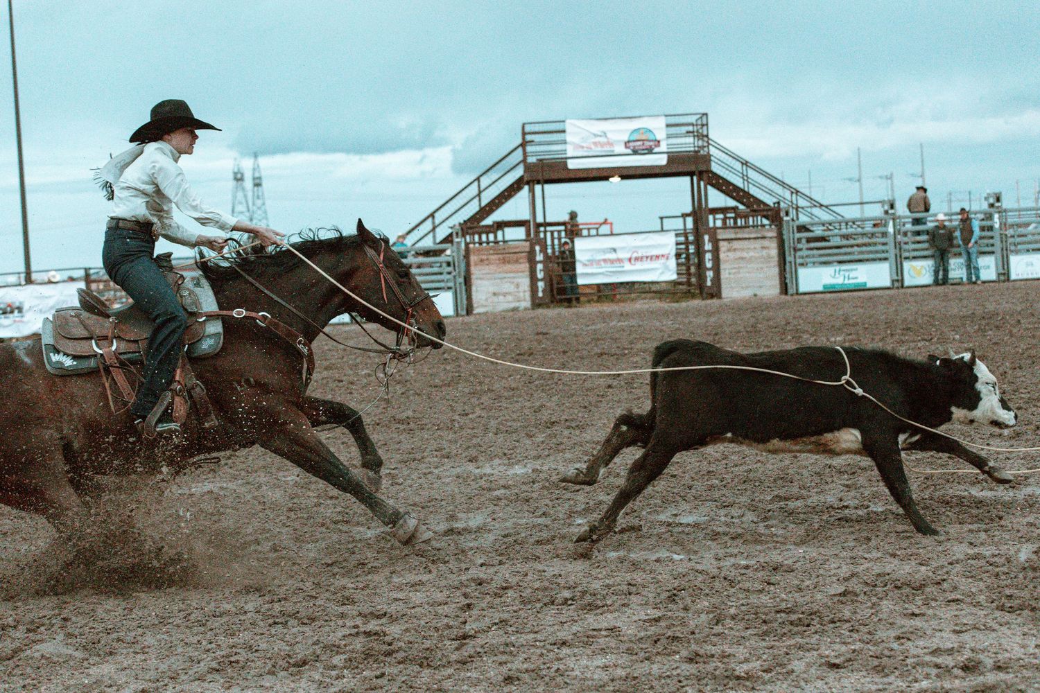 Sequence of a horse and rider racing across a dusty rodeo arena during a barrel racing competition.