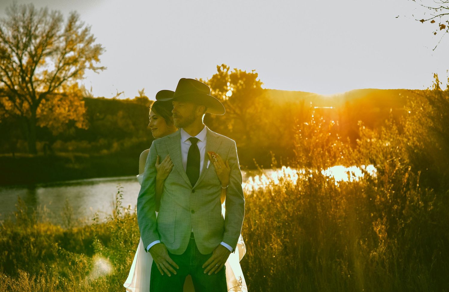 A western bride and groom in the western nebraska sunset with golden hues in the backdrop along the North Platte River