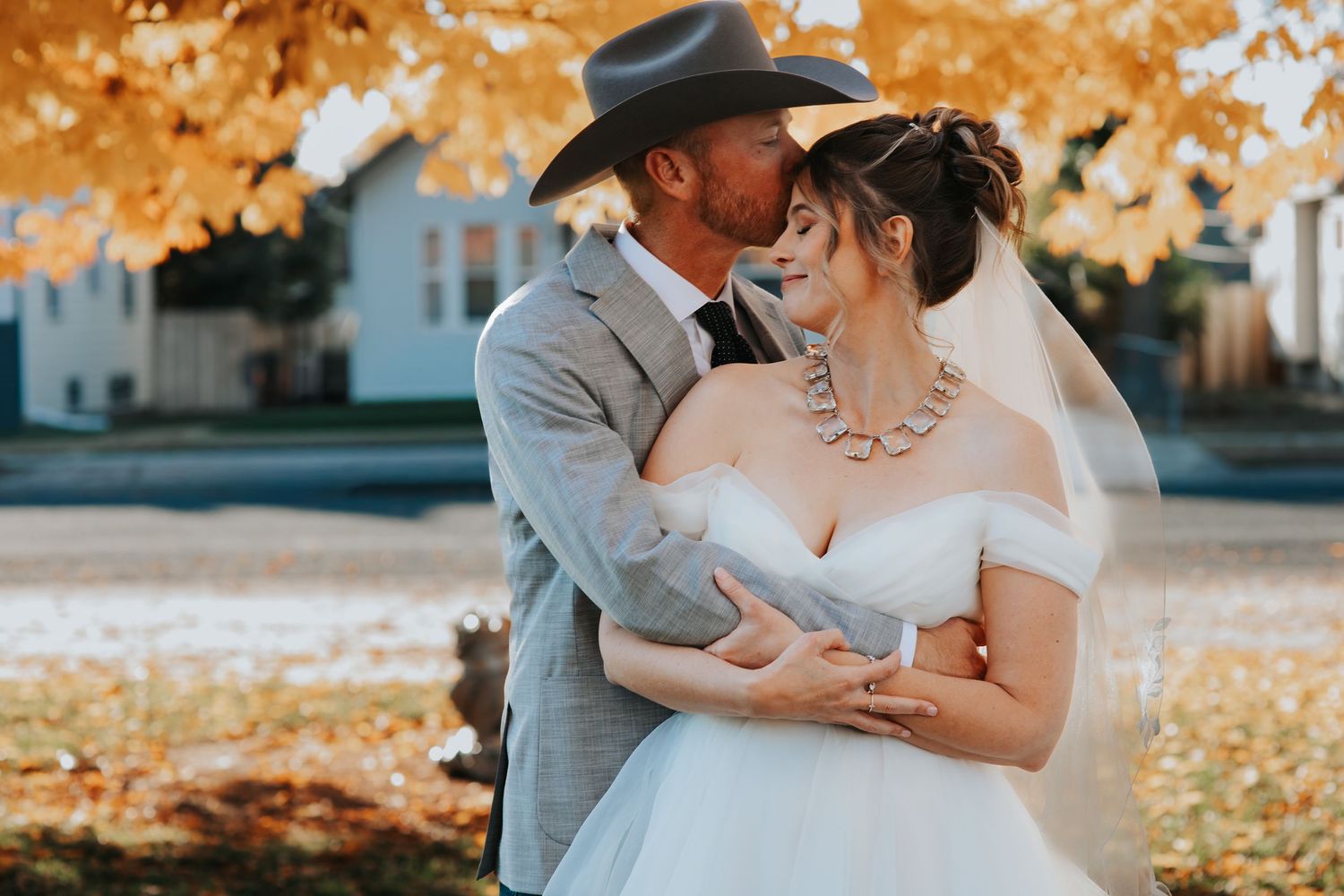 A couple shares a romantic moment under golden autumn leaves in a wedding photography session. In Scottsbluff Nebraska