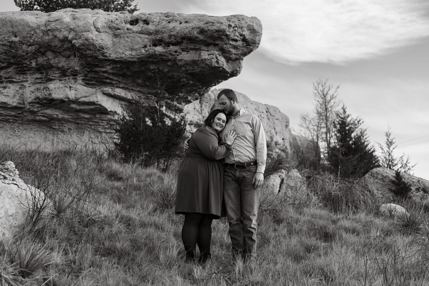 A engaged couple poses under a rocky landscape in Nebraska during engagement pictures.