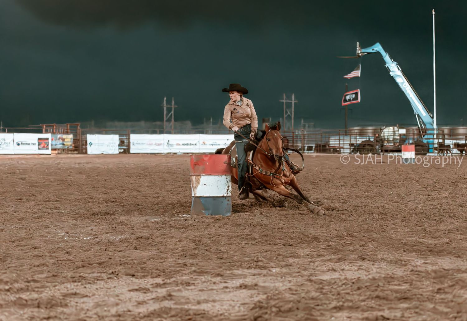 Horse and rider performing in a dusty rodeo arena during a competition event.