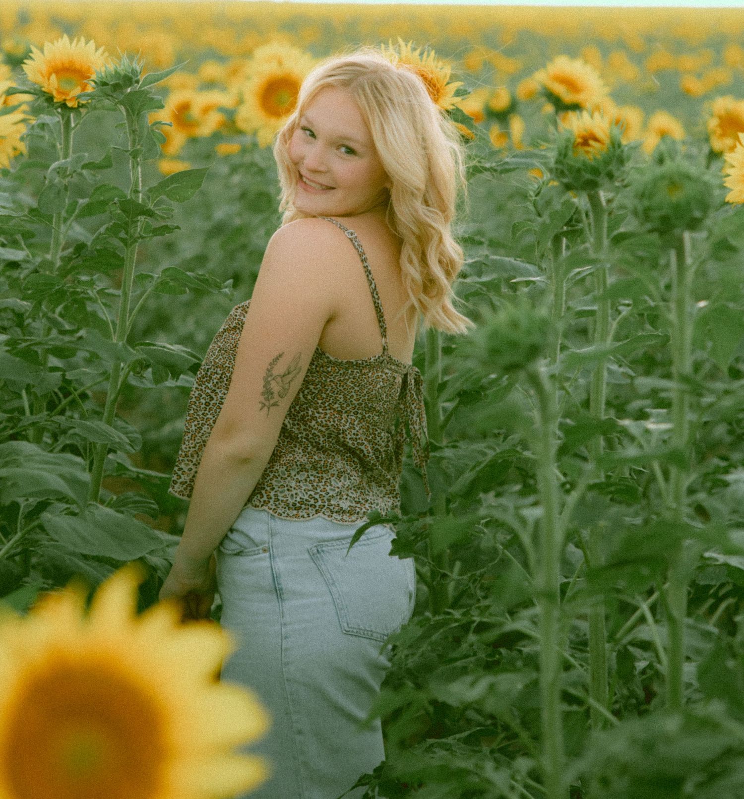 A highschool senior in a sunflower field in Kimball Nebraska posing for high school senior photography session