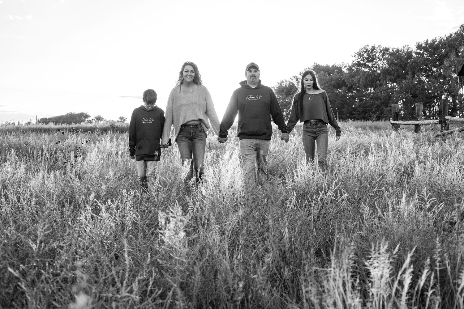 A group of people walking through a tall grassy meadow on a sunny day, viewed from behind in Nebraska.