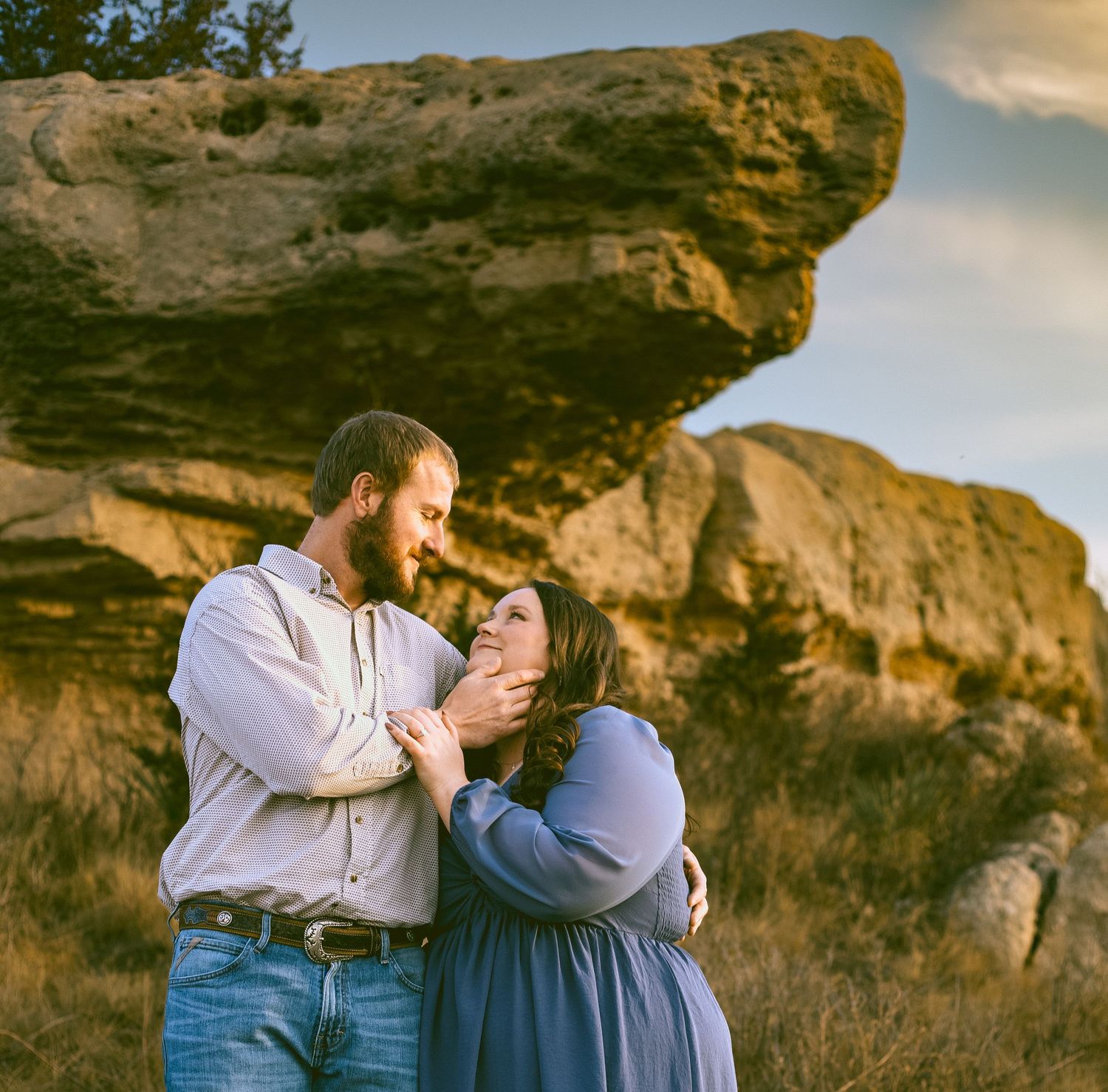 A couple shares tender moments against a backdrop of rocky cliffs and golden sunlight at sunset in Sidney Nebraska