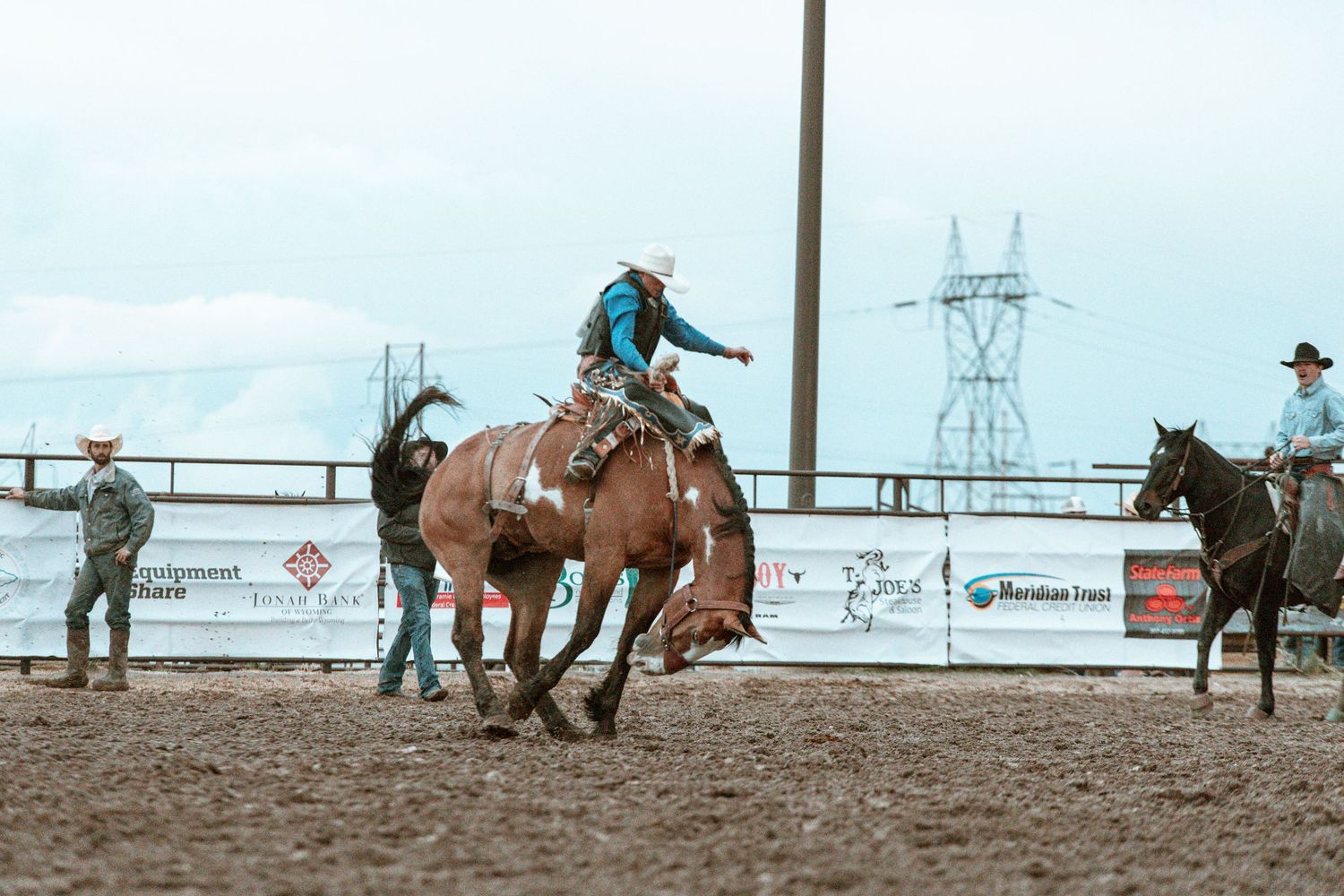 Wide angle view of cowboys and horses performing in a professional rodeo arena.