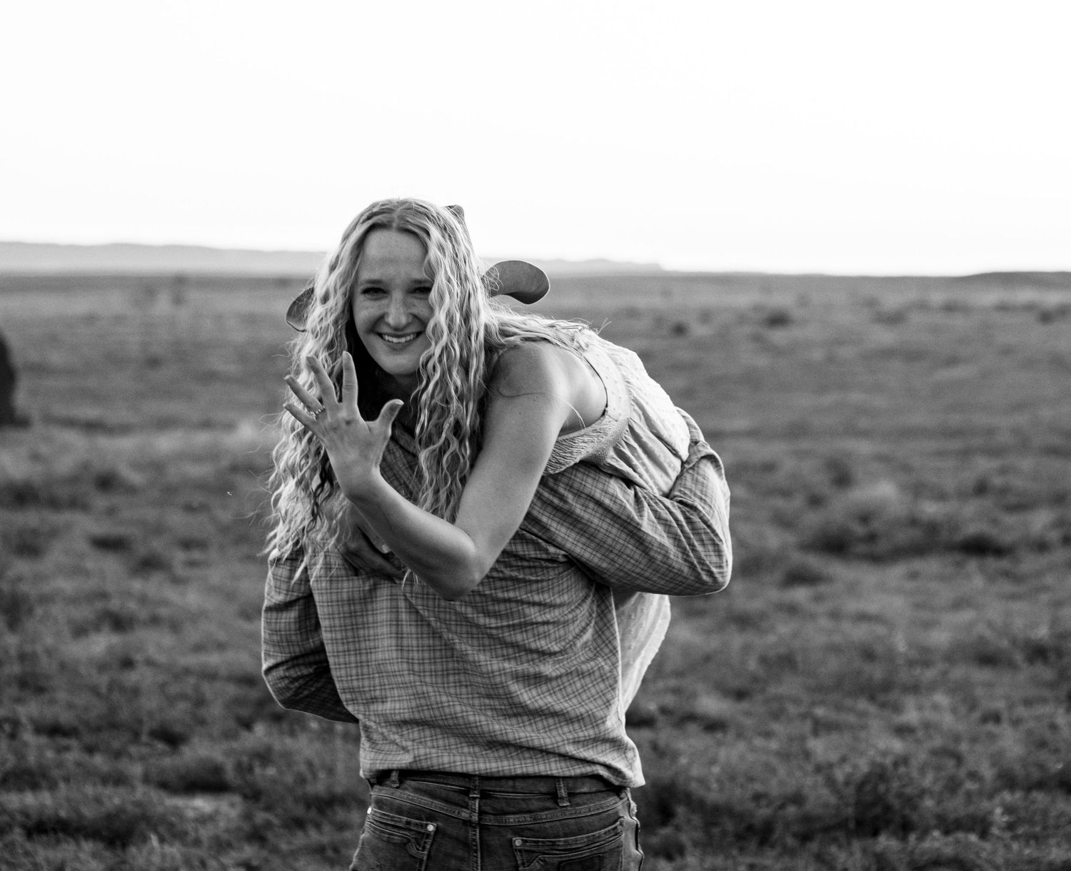 A engaged couple in western attire in black and white in a hay field located in Western Nebraska.