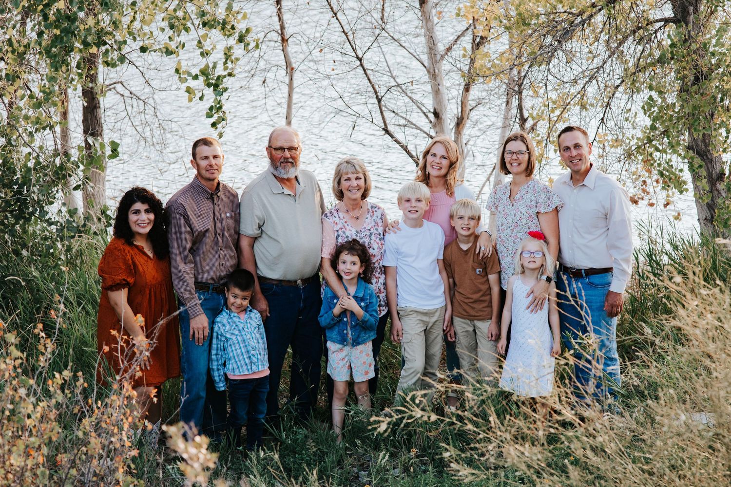 A large family poses near a lake for generational images during a family session in nebraska