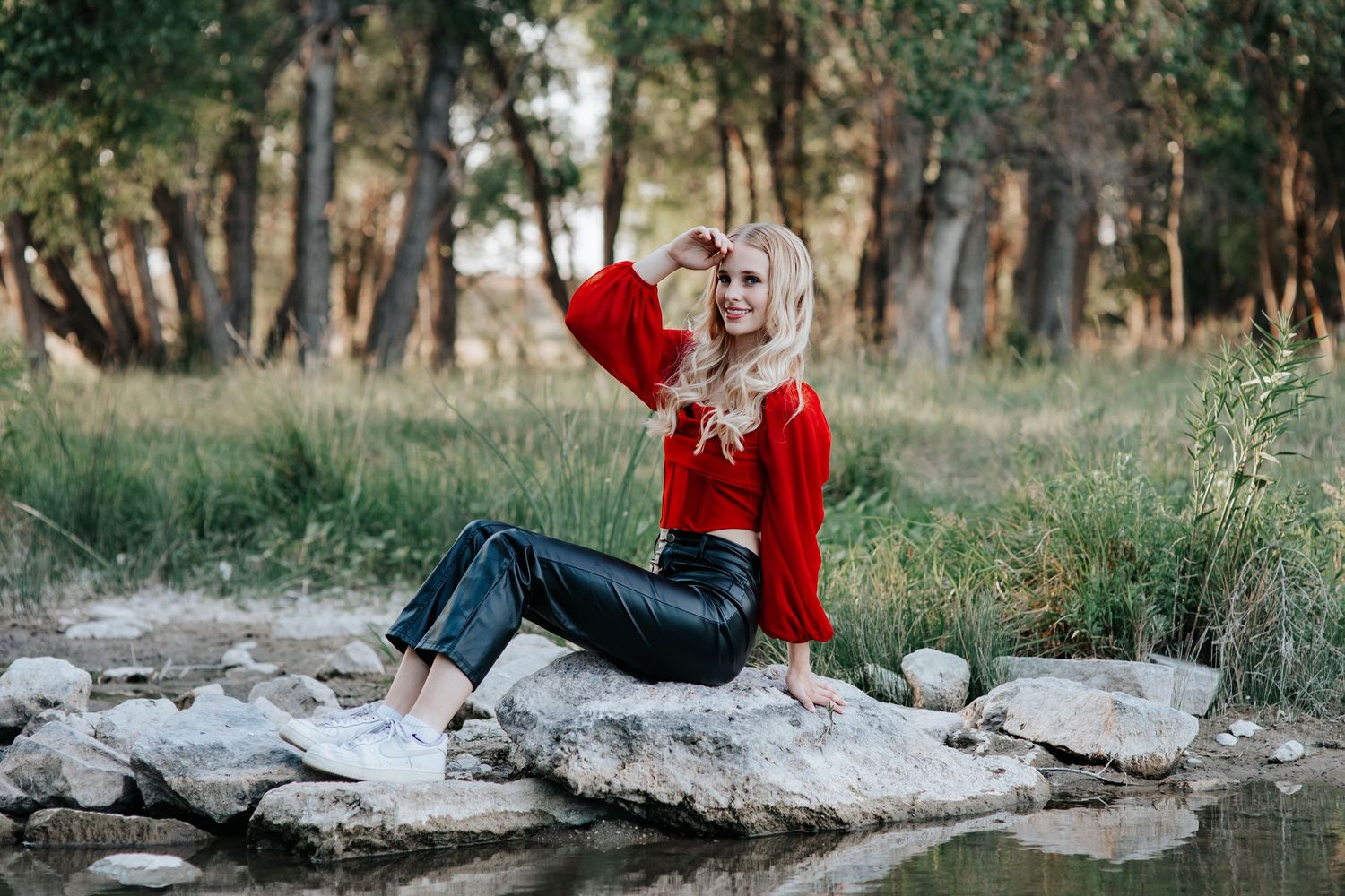 A senior posing for high school senior portraits by a creek in Western Nebraska.