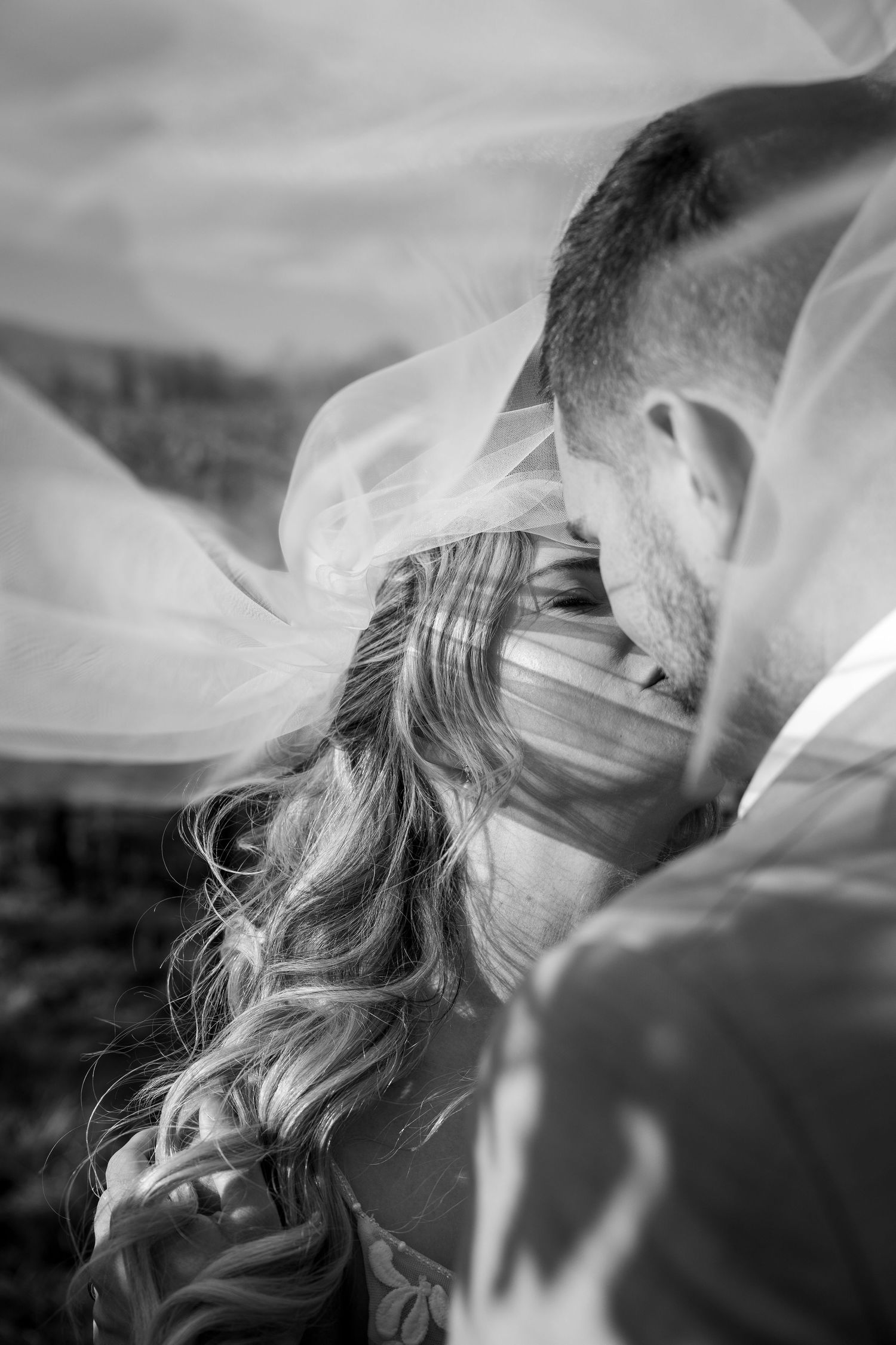 Bride and groom kissing with veil over them, in Cromwell wedding.