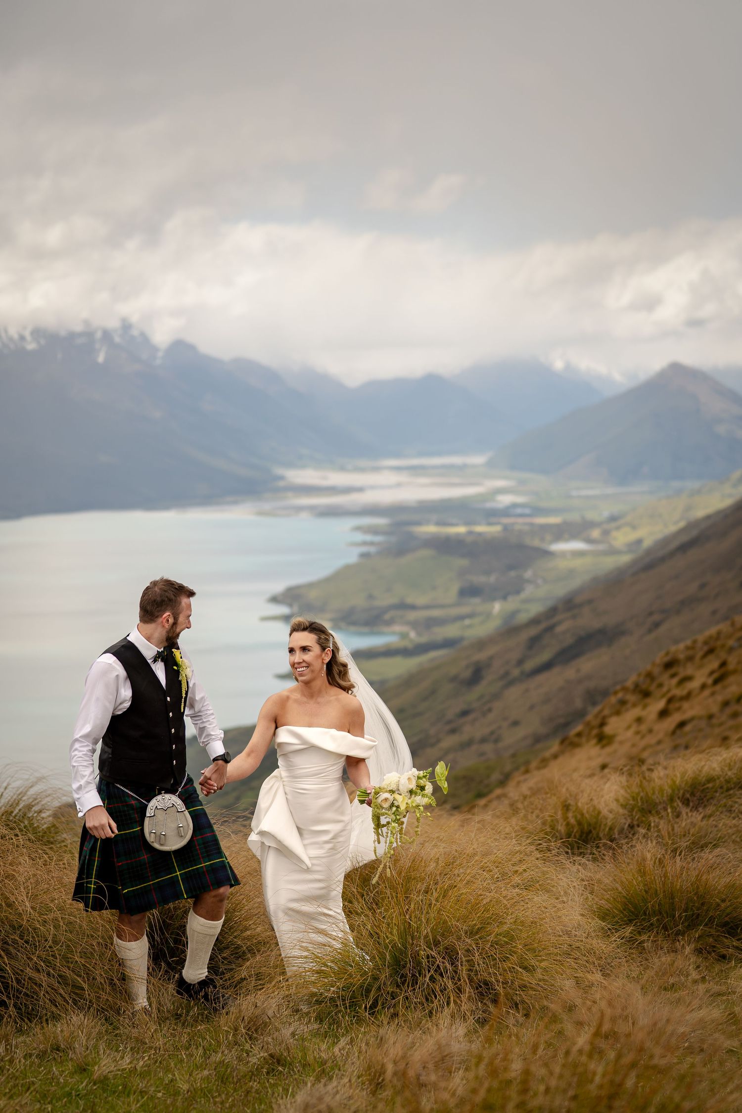 Bride and Groom portrait in mountains, with lake in the background. Queenstown New Zealand.