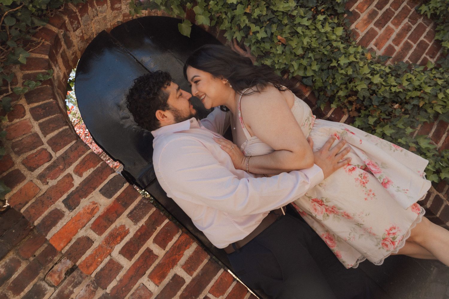 Couple sharing a romantic moment standing together in a brick alcove surrounded by lush green ivy.