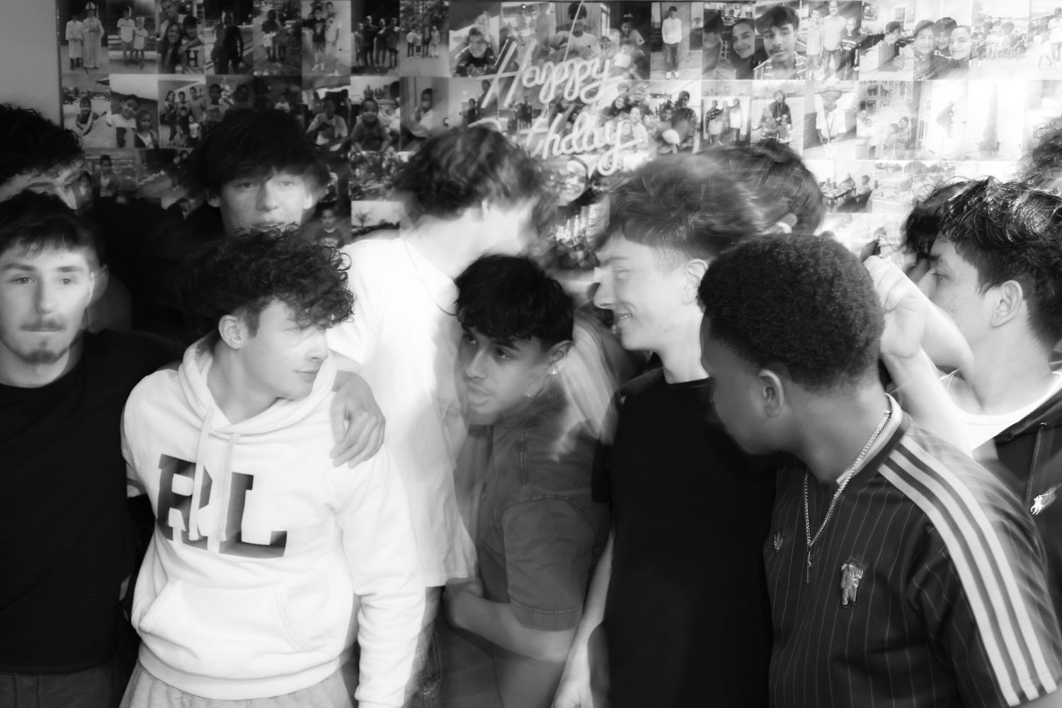 Black and white photo of a group of young men socializing at an indoor party or gathering.
