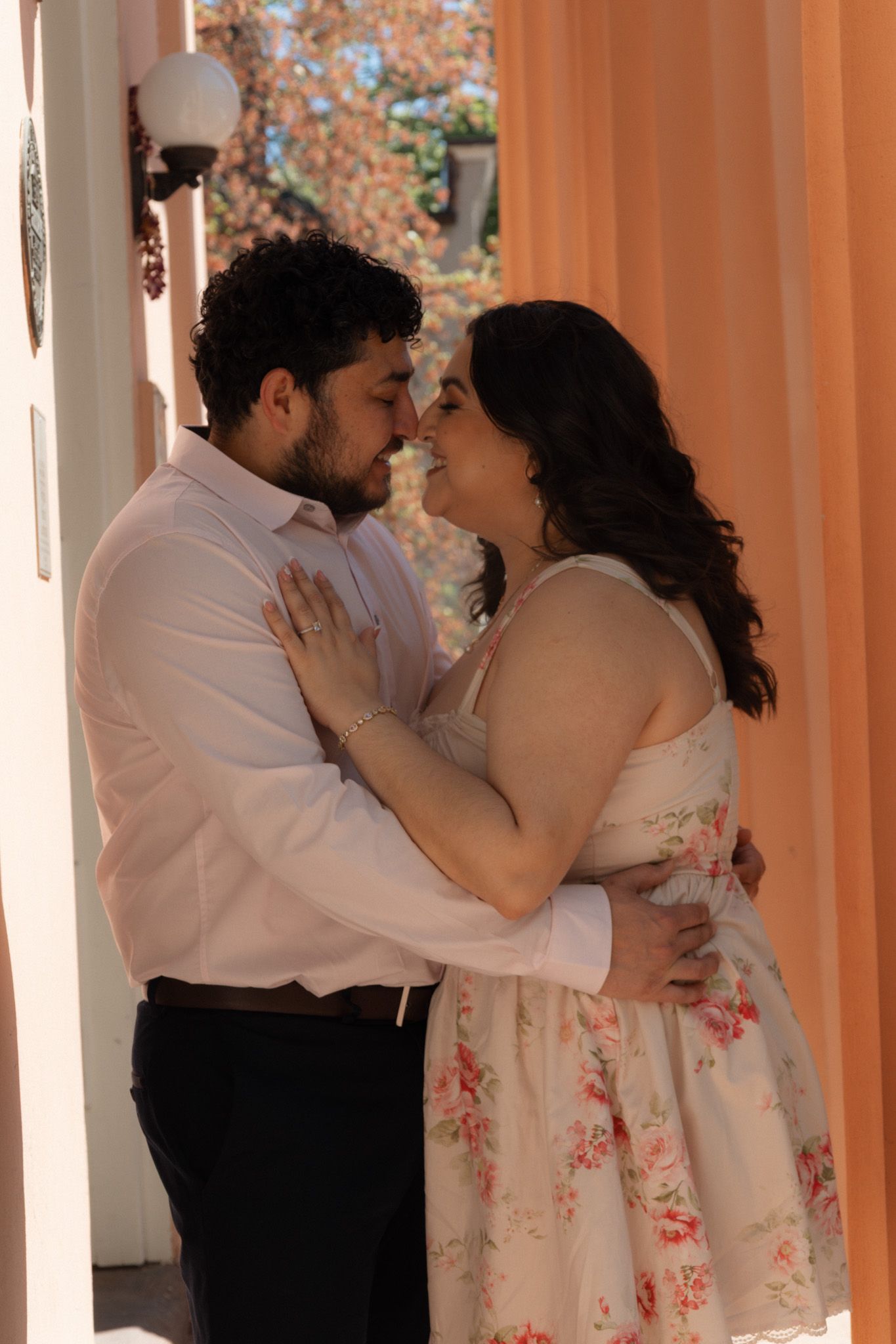 Couple sharing a romantic moment, man in white shirt and woman in floral dress embracing outdoors.