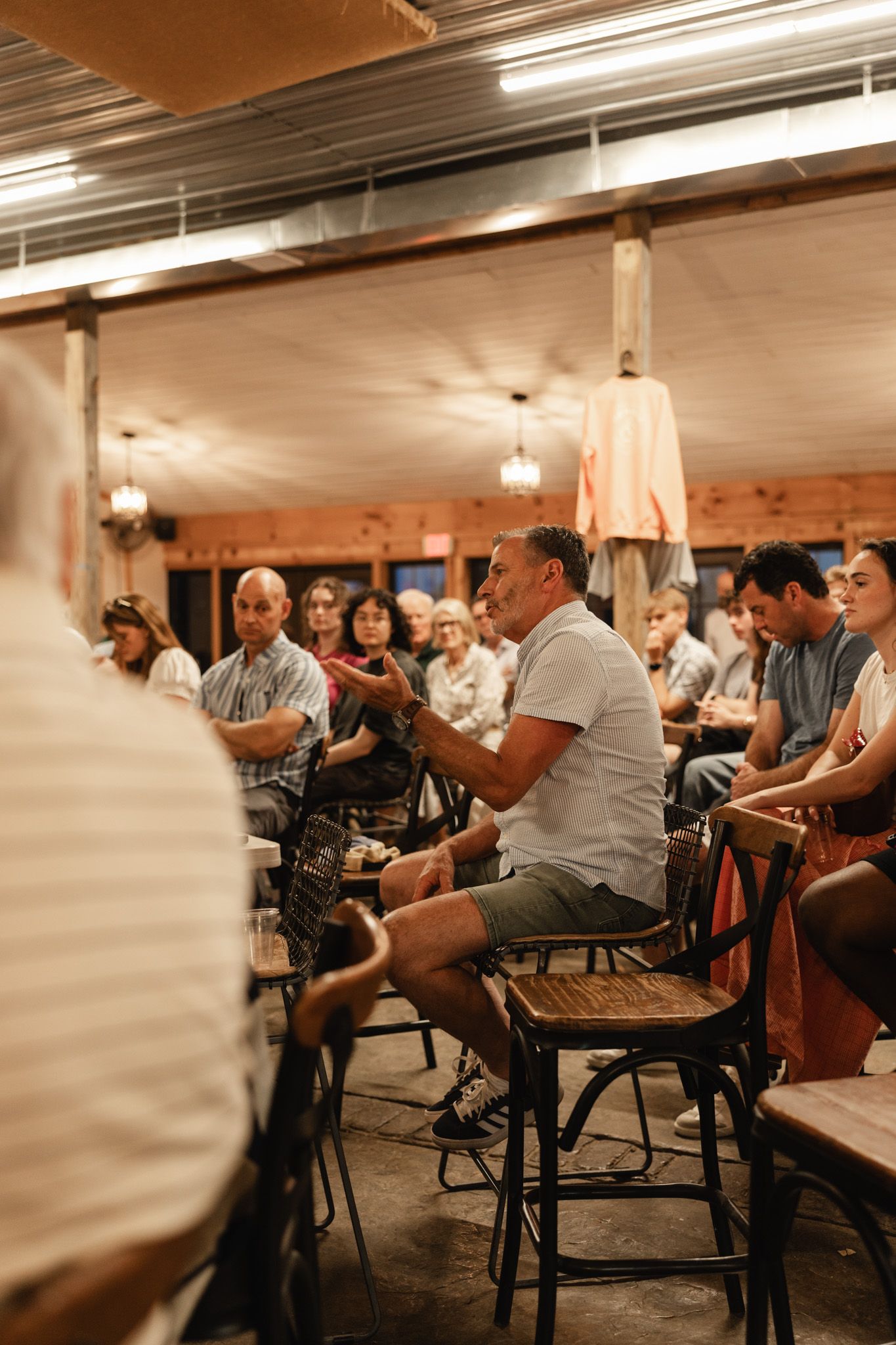 People seated in a rustic barn venue during an indoor gathering or community event.