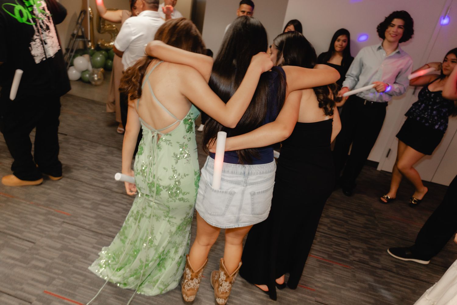 Group of young women in formal dresses dancing together at a party celebration event.