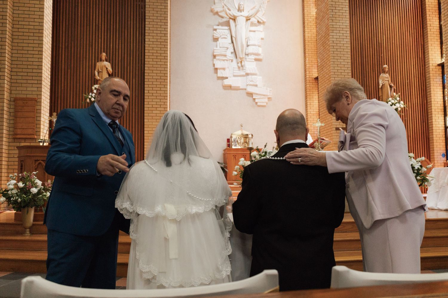 Couple exchanging wedding vows at church altar with officiant and witness in elegant ceremony.