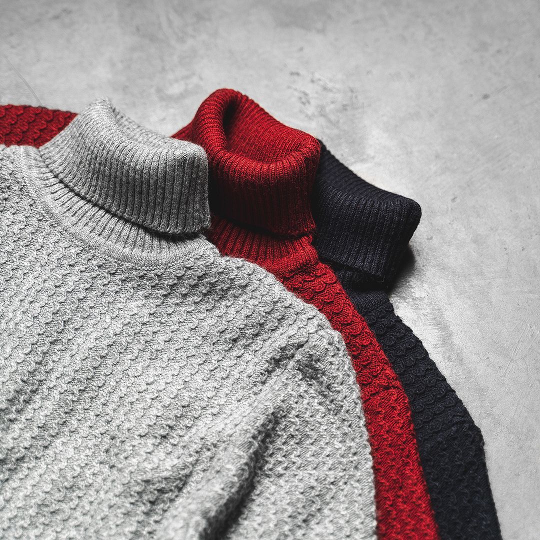 Collection of knit turtleneck sweaters in white, red, grey and black displayed on light background.