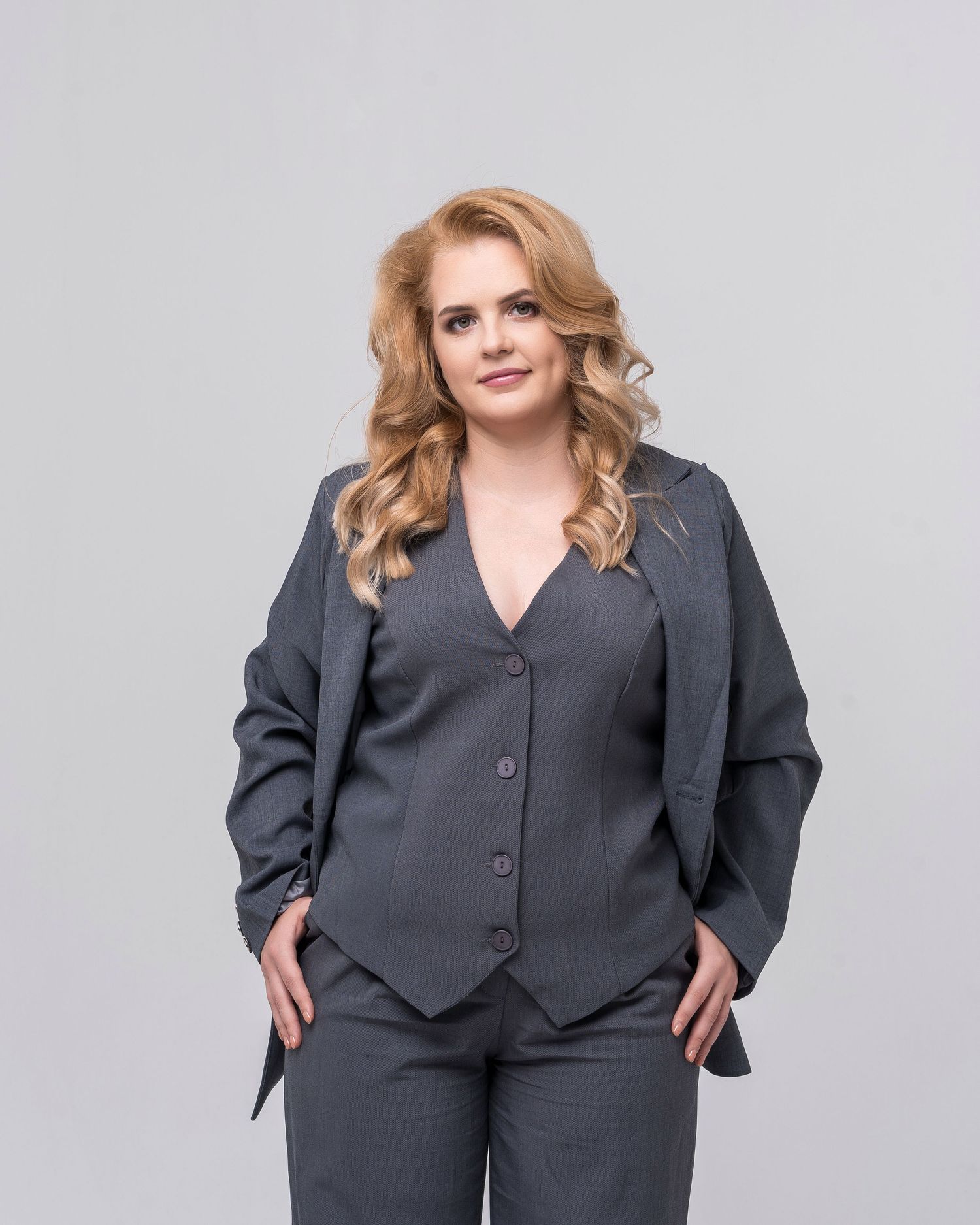 Professional portrait series of a woman in a dark gray business suit against white background.