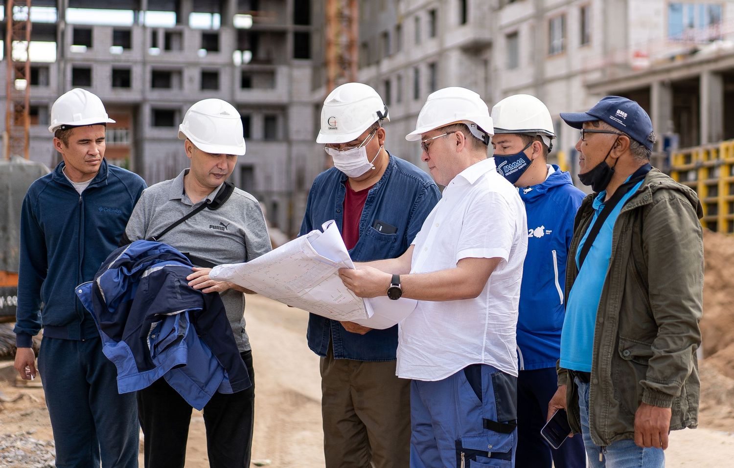 Team of construction workers discussing project plans at a large building development.