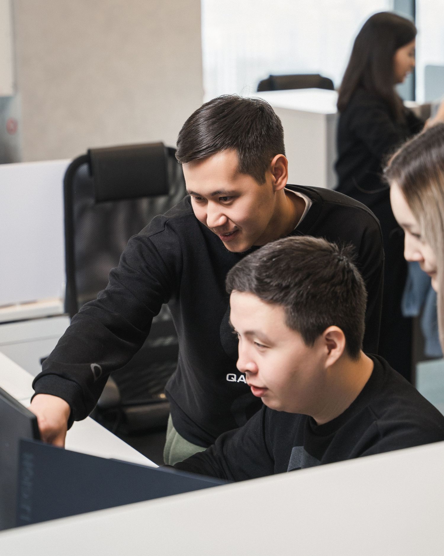 Colleagues collaborating while looking at computer screen in office workspace.