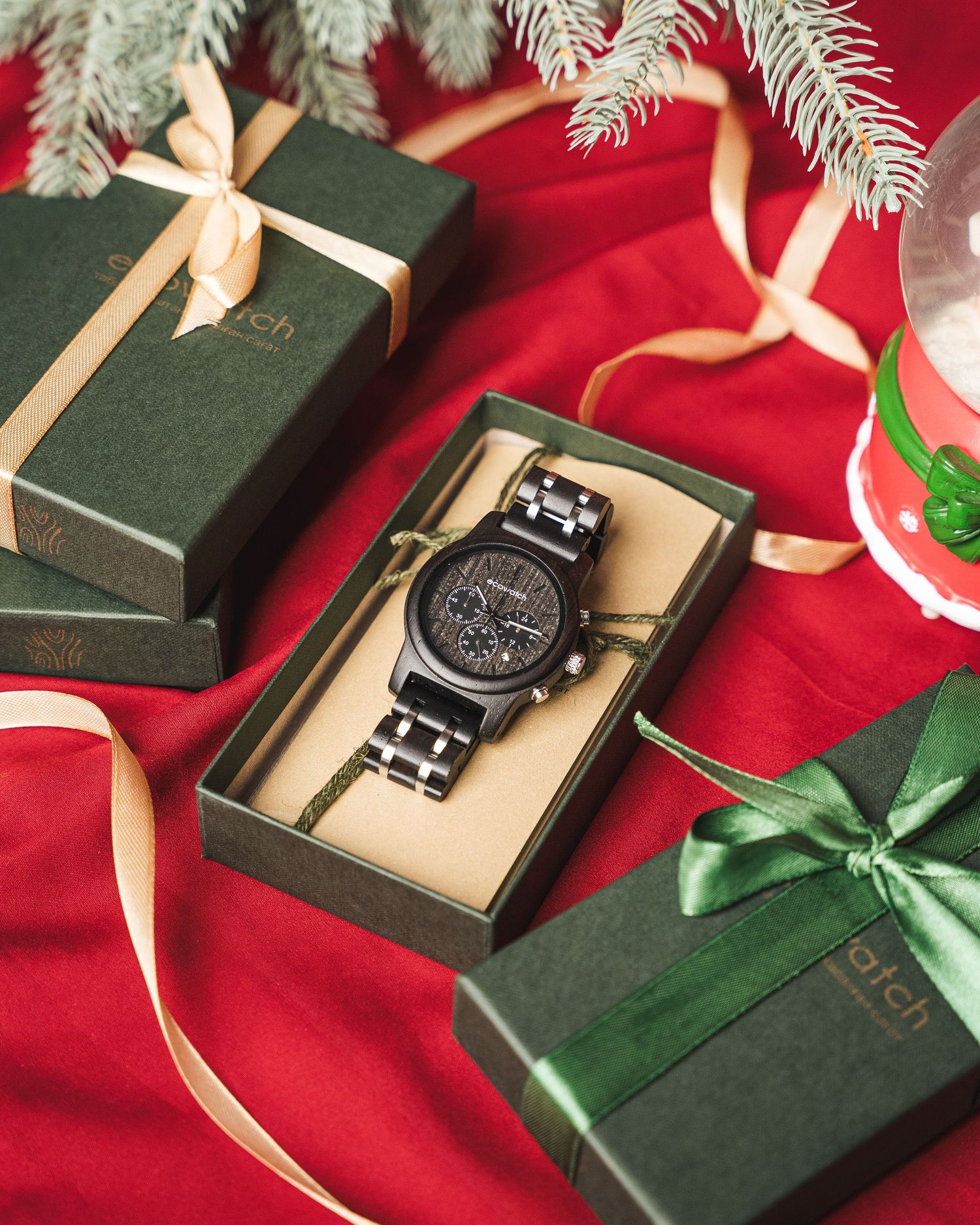 Luxury watch gift box with holiday decorations on red and green background.