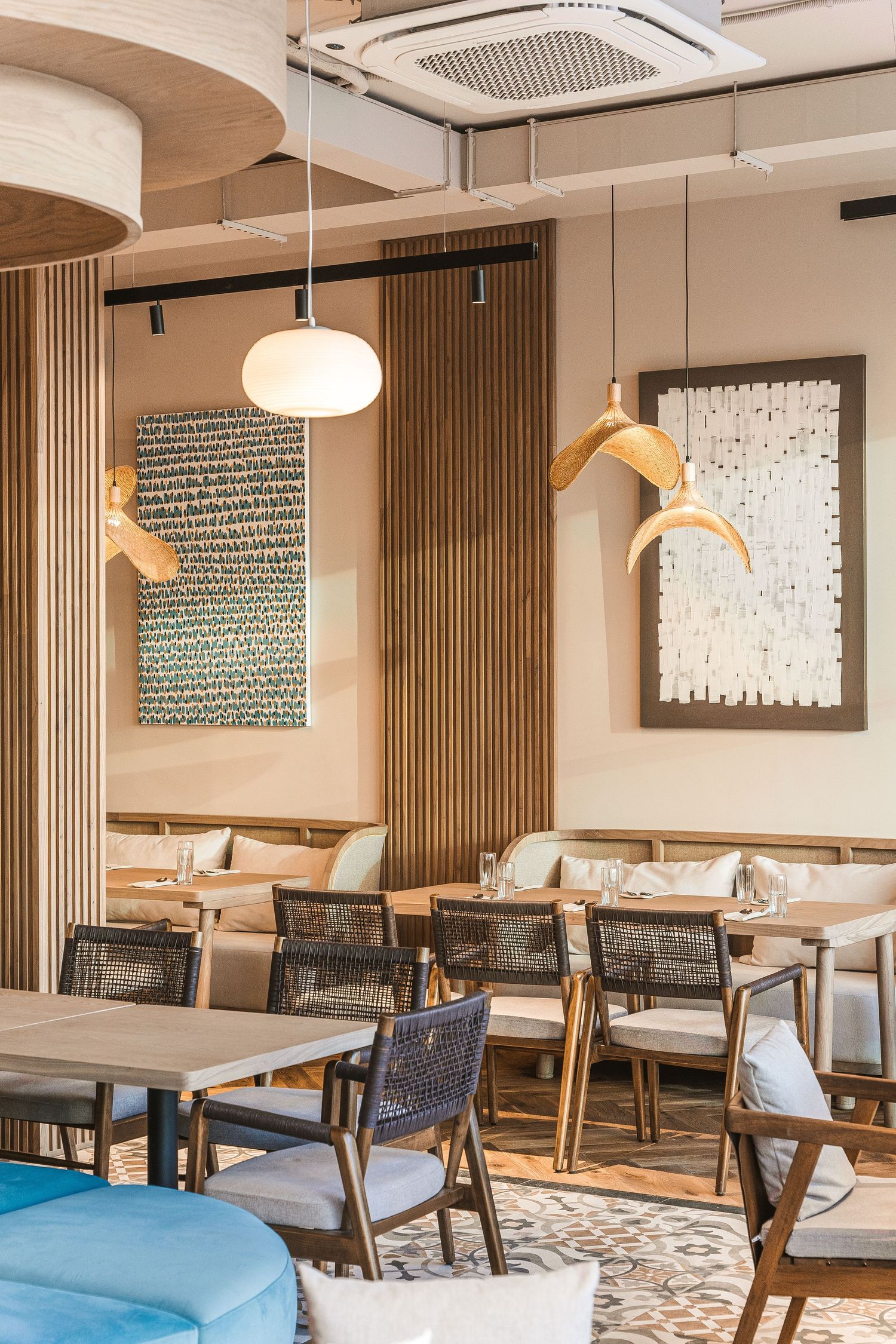 Contemporary restaurant space with textured wall art, wooden slat details, and comfortable seating arrangements.
