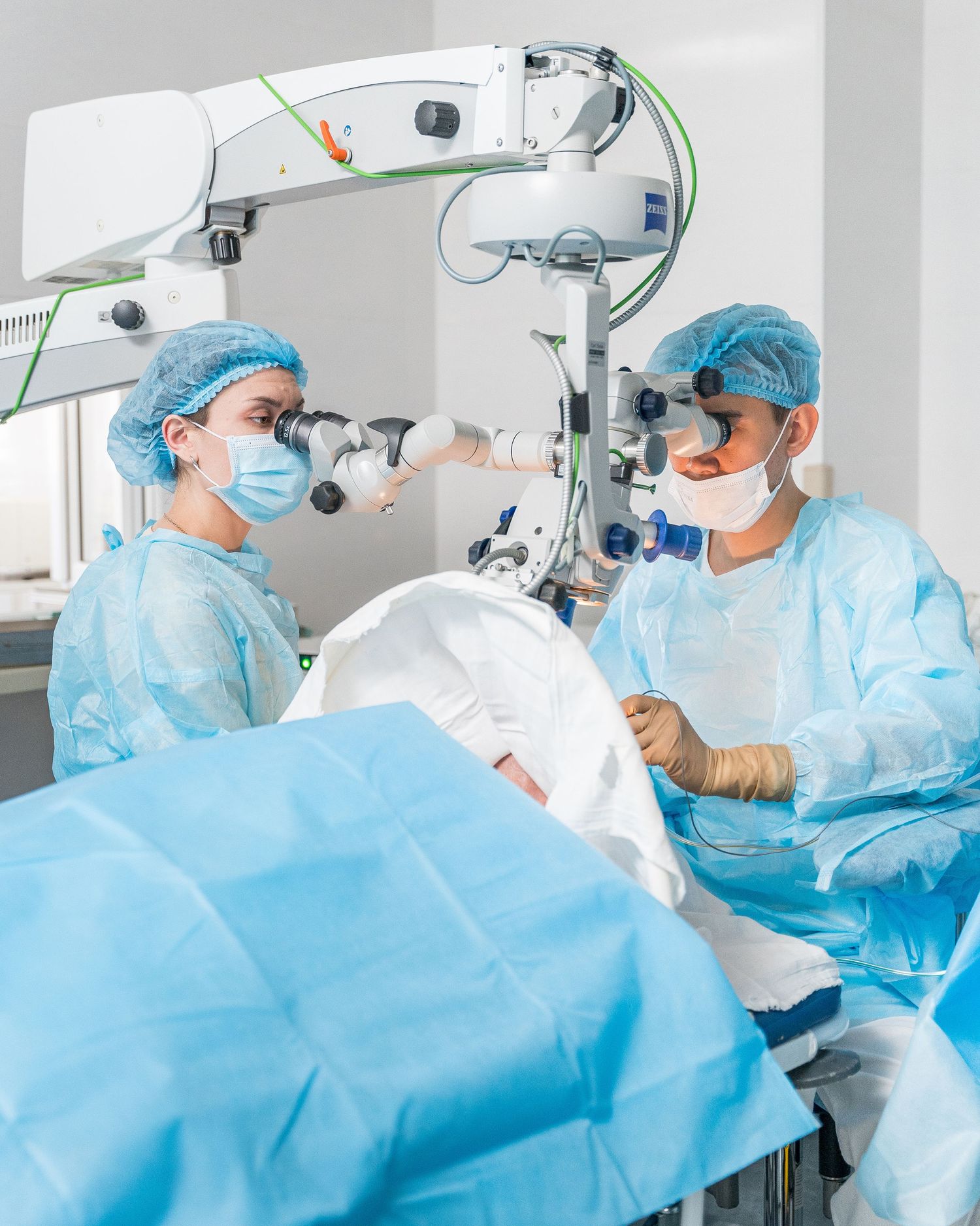 Surgical team conducting operation using sophisticated medical equipment in sterile setting.