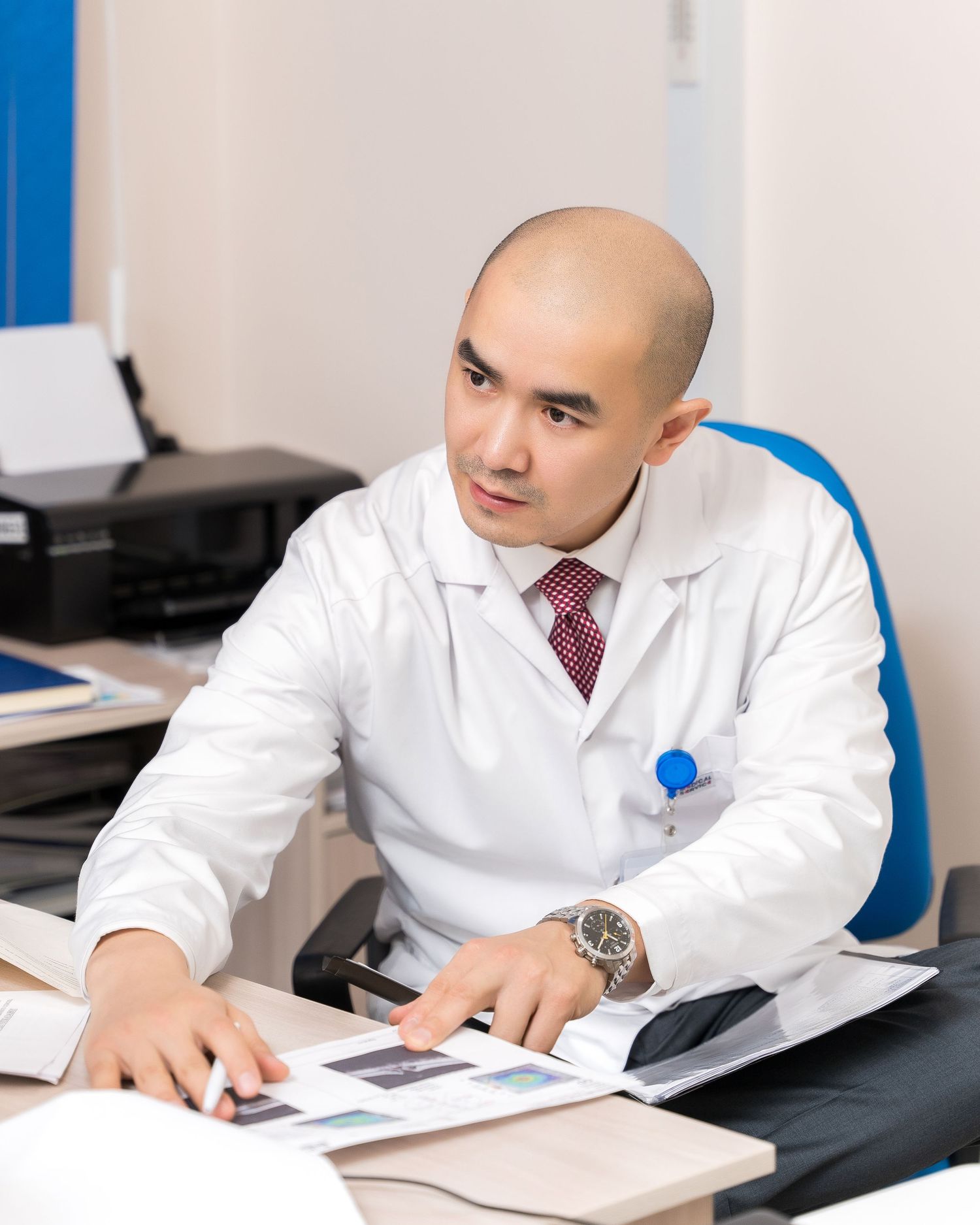 Medical professional in white coat reviewing documents at desk.