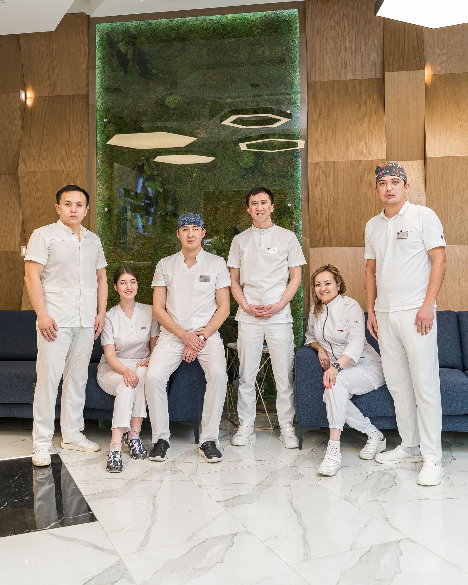 Medical team in white uniforms posing together in modern healthcare facility.