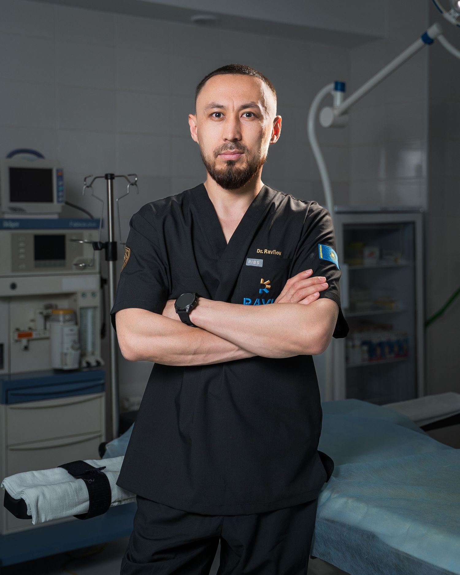 Healthcare provider in dark scrubs posing confidently in modern medical facility.