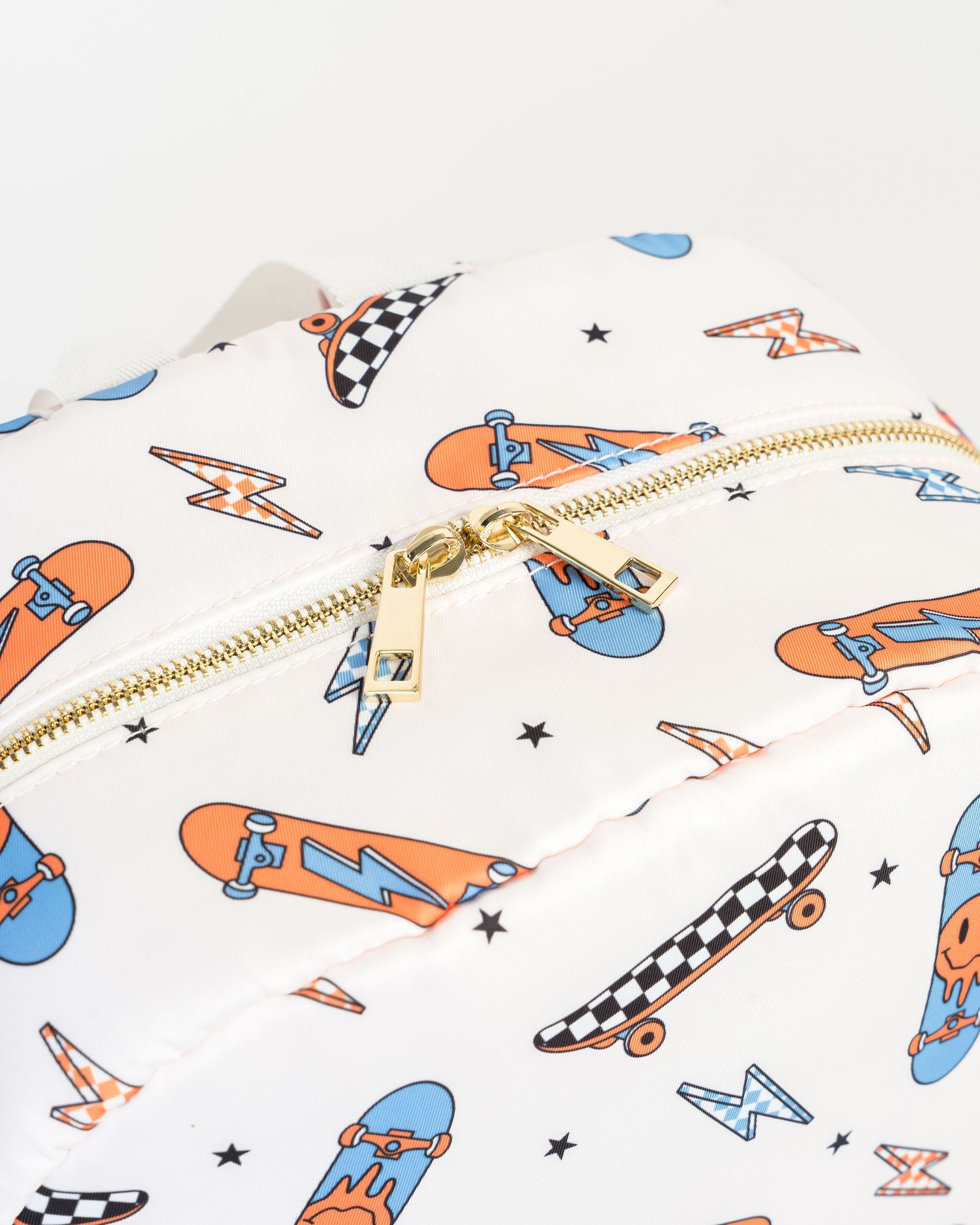Close-up of skateboard pattern fabric with checkered details and gold zipper.