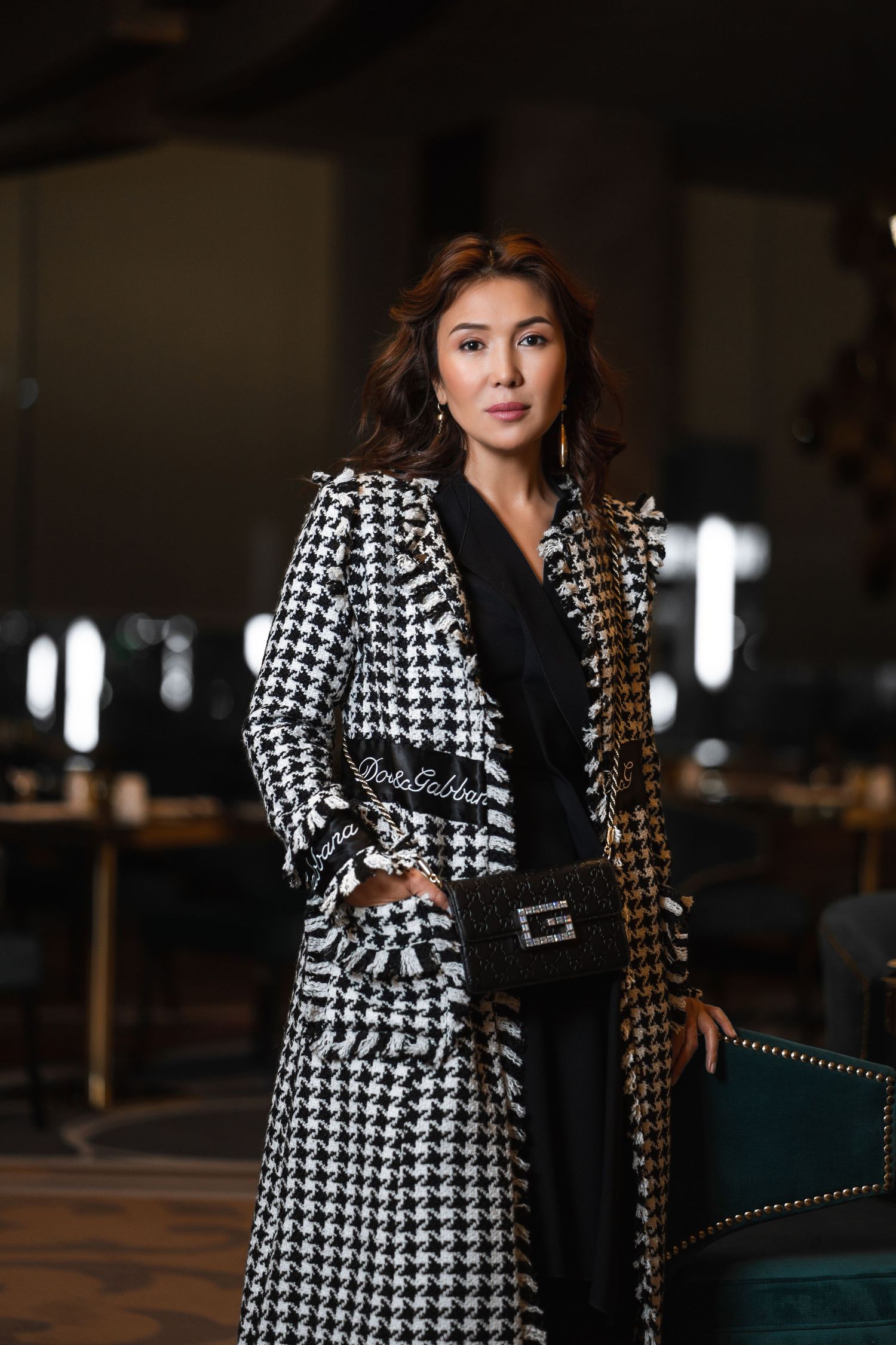 Stylish black and white houndstooth coat worn in dramatic indoor lighting.