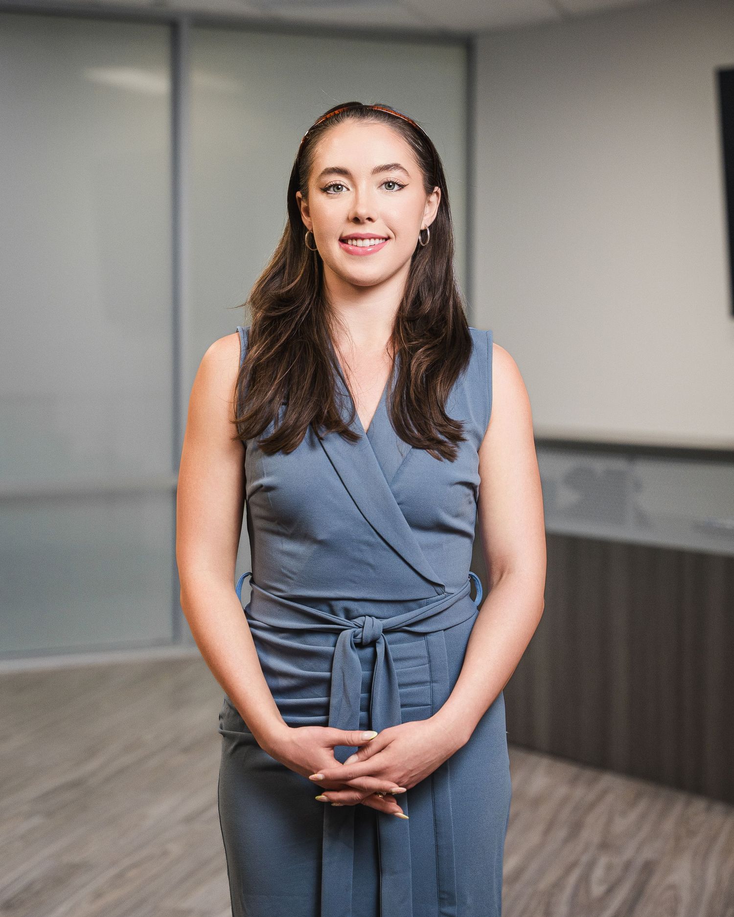 Professional portrait in an office setting with modern grey walls and wood flooring.