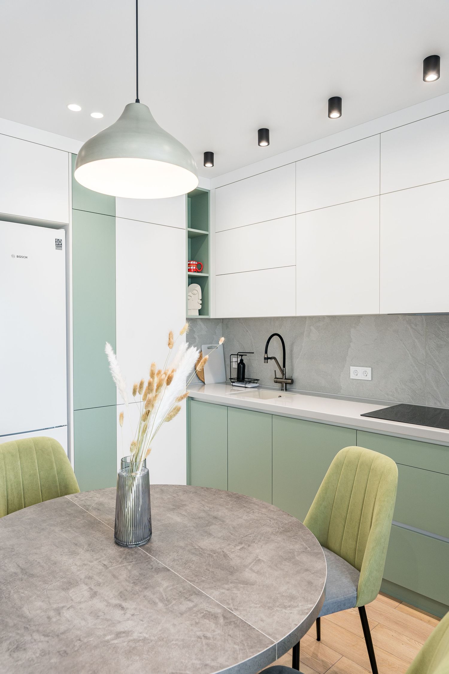 Contemporary kitchen with mint green cabinets, gray round table, and velvet dining chairs.