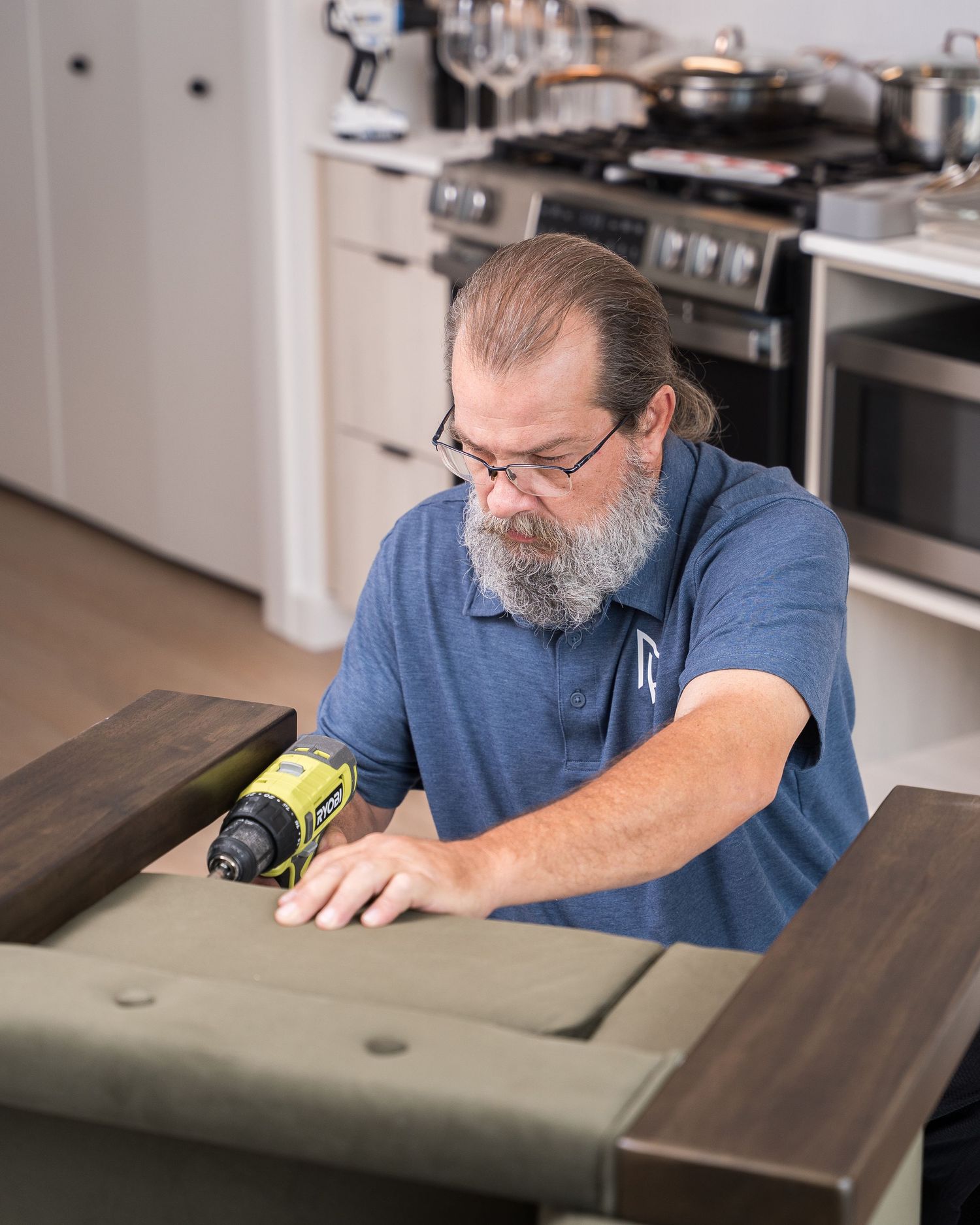 Craftsman in blue shirt carefully examining wooden furniture details.