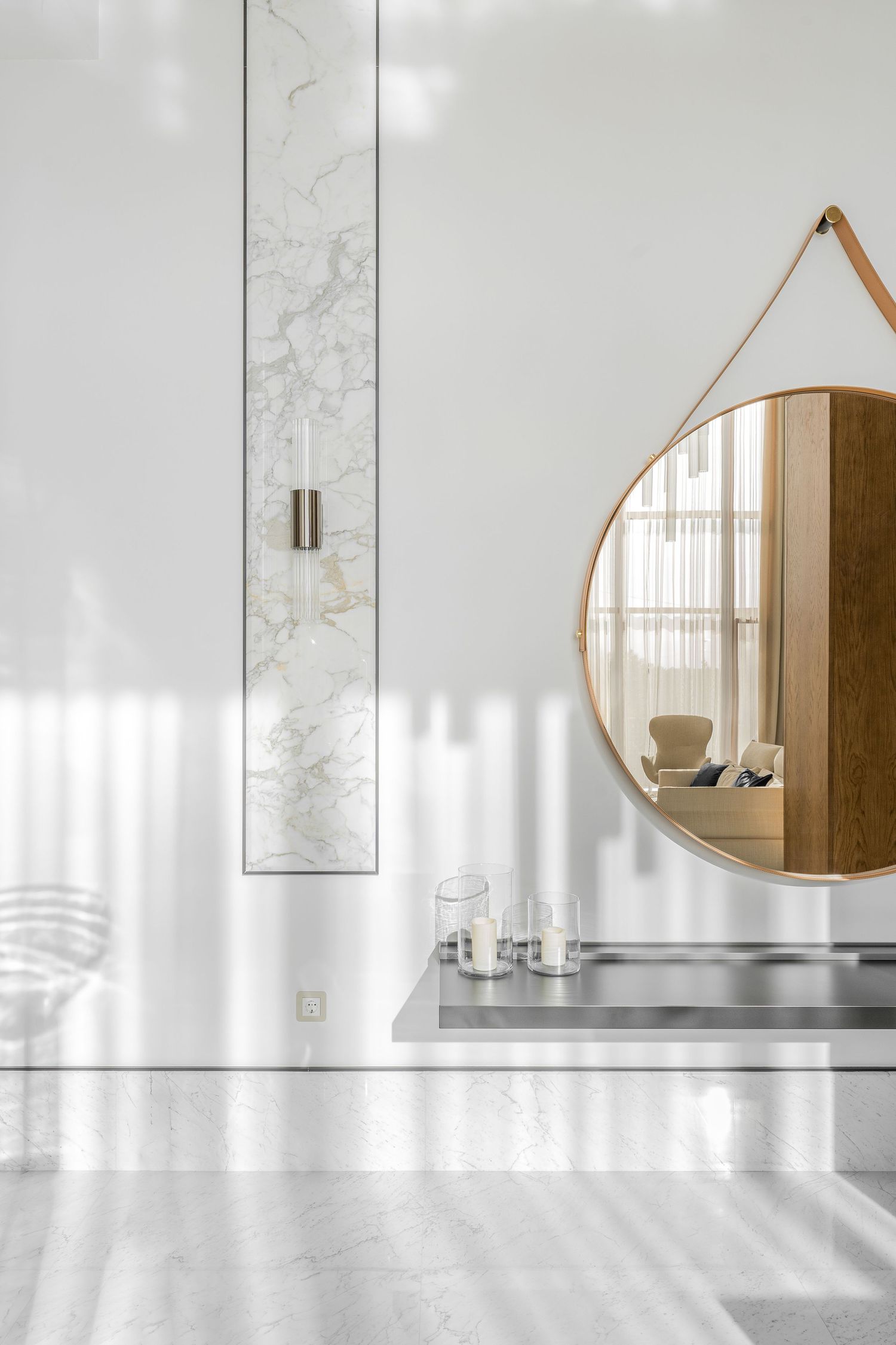 Bright white interior space with round mirror and minimalist wall sconces.
