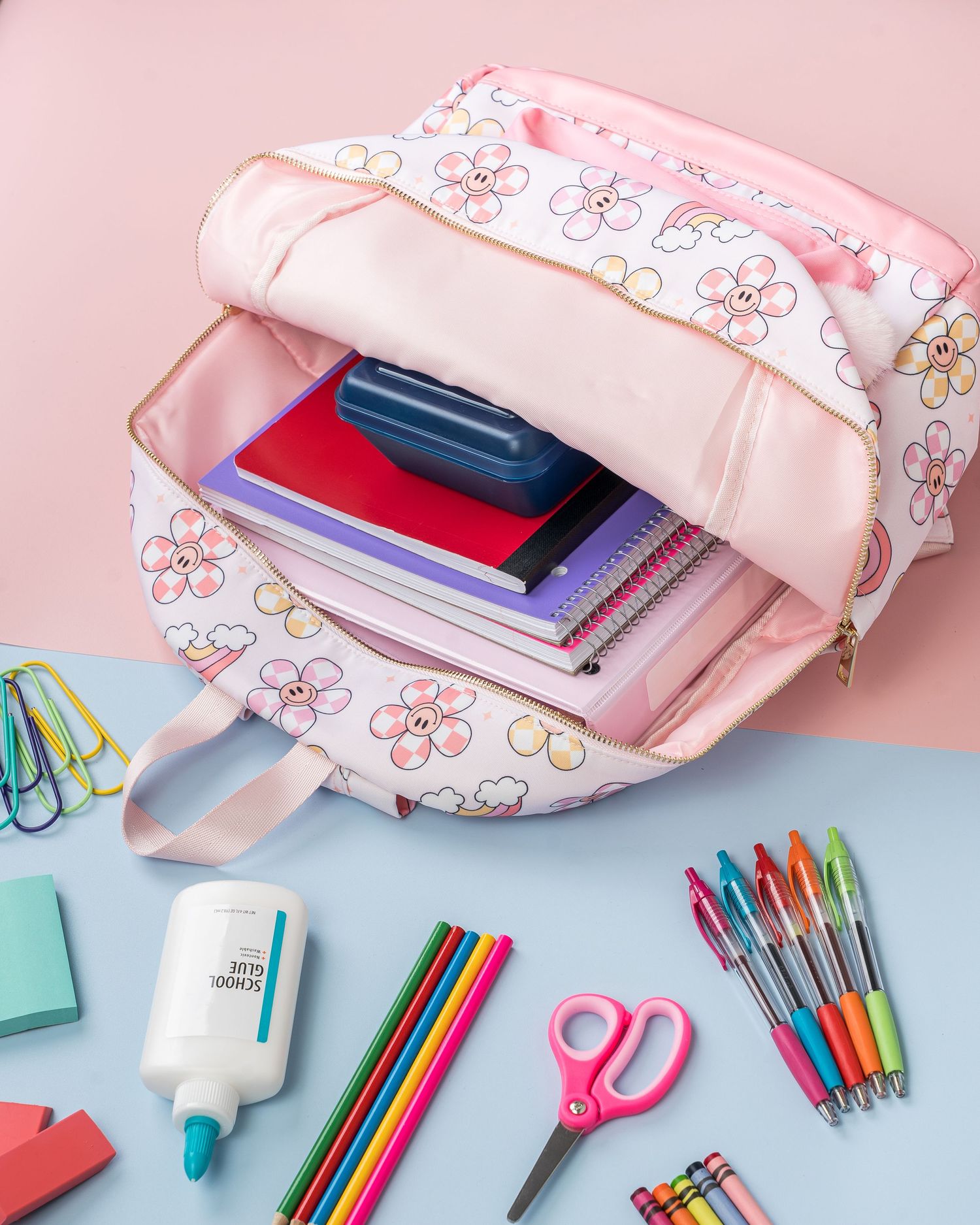 Pink floral pencil case with colorful school supplies and stationery items arranged on light blue background.