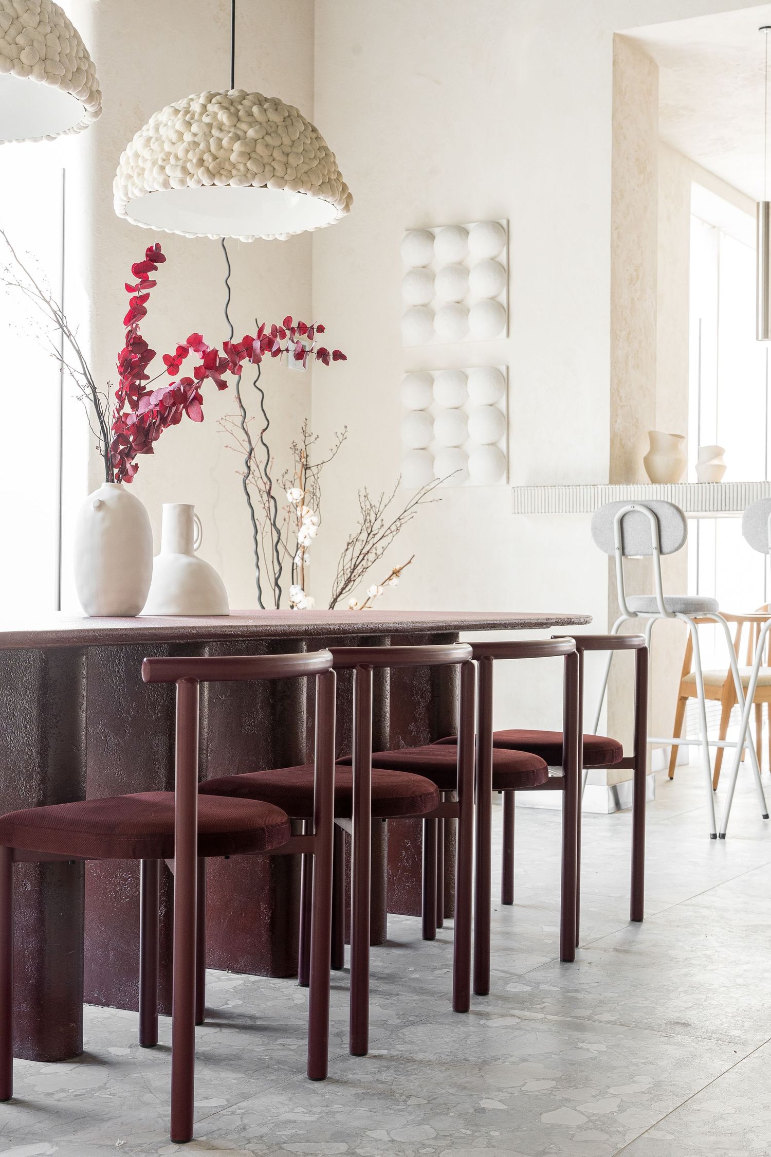 Restaurant space with dark wood tables and white pendant lights creating an elegant atmosphere.