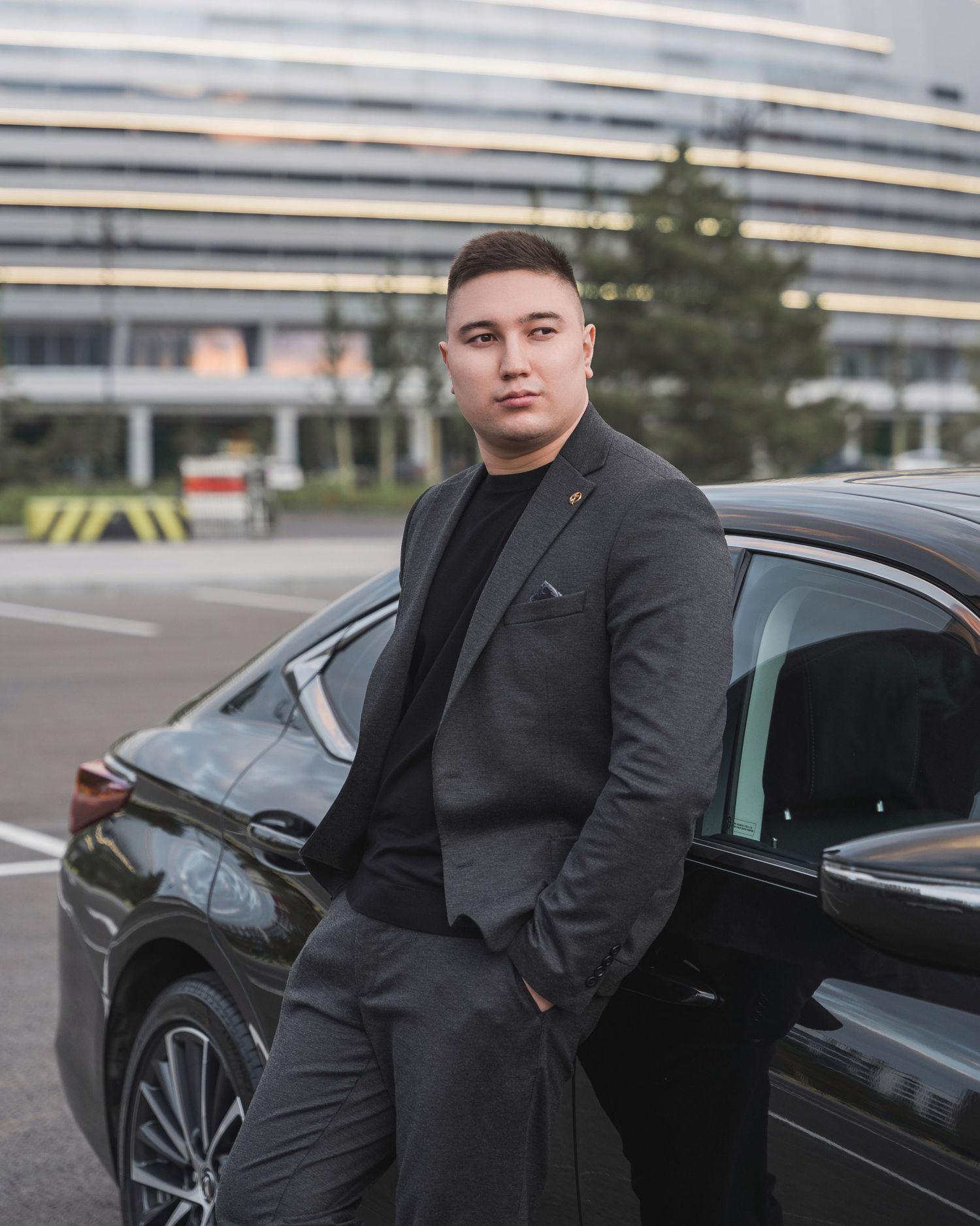 Business professional standing next to luxury car in corporate parking lot.